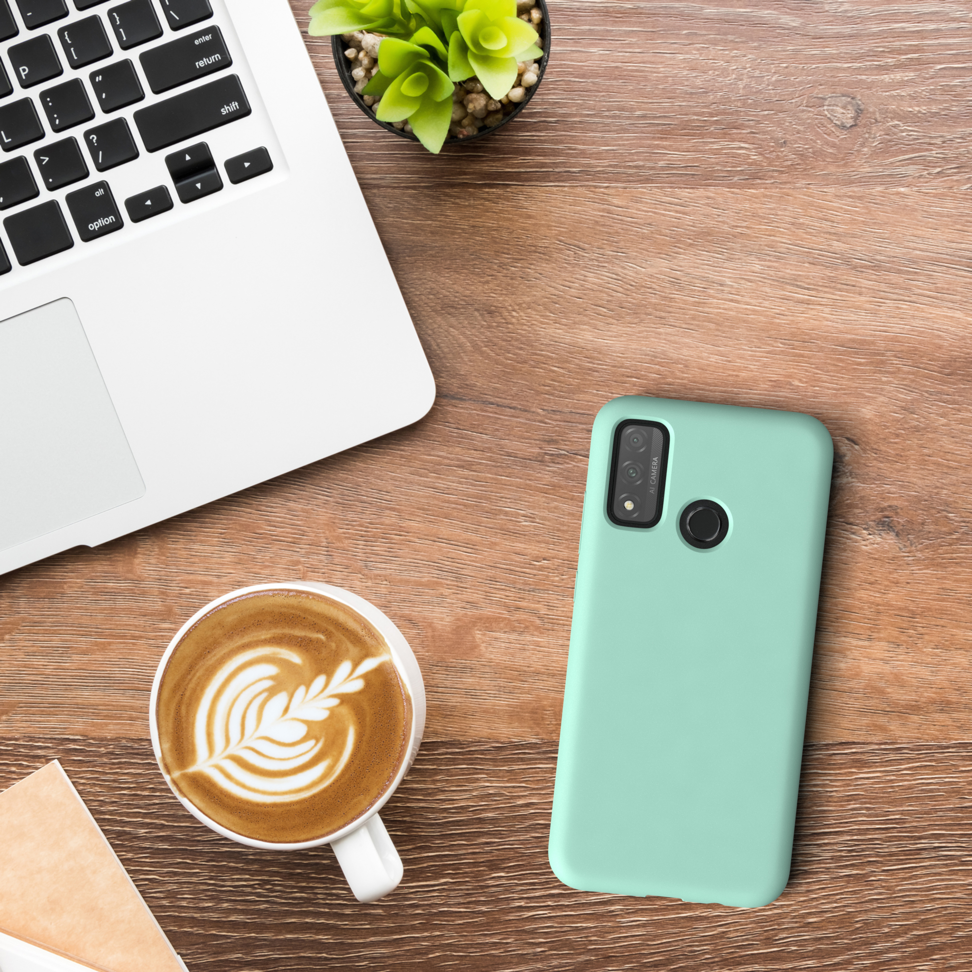 Laptop, Kaffee und Handyhülle auf einem Holztisch. Mintfarbene Handyhülle neben einer Kaffeetasse mit Latte Art.