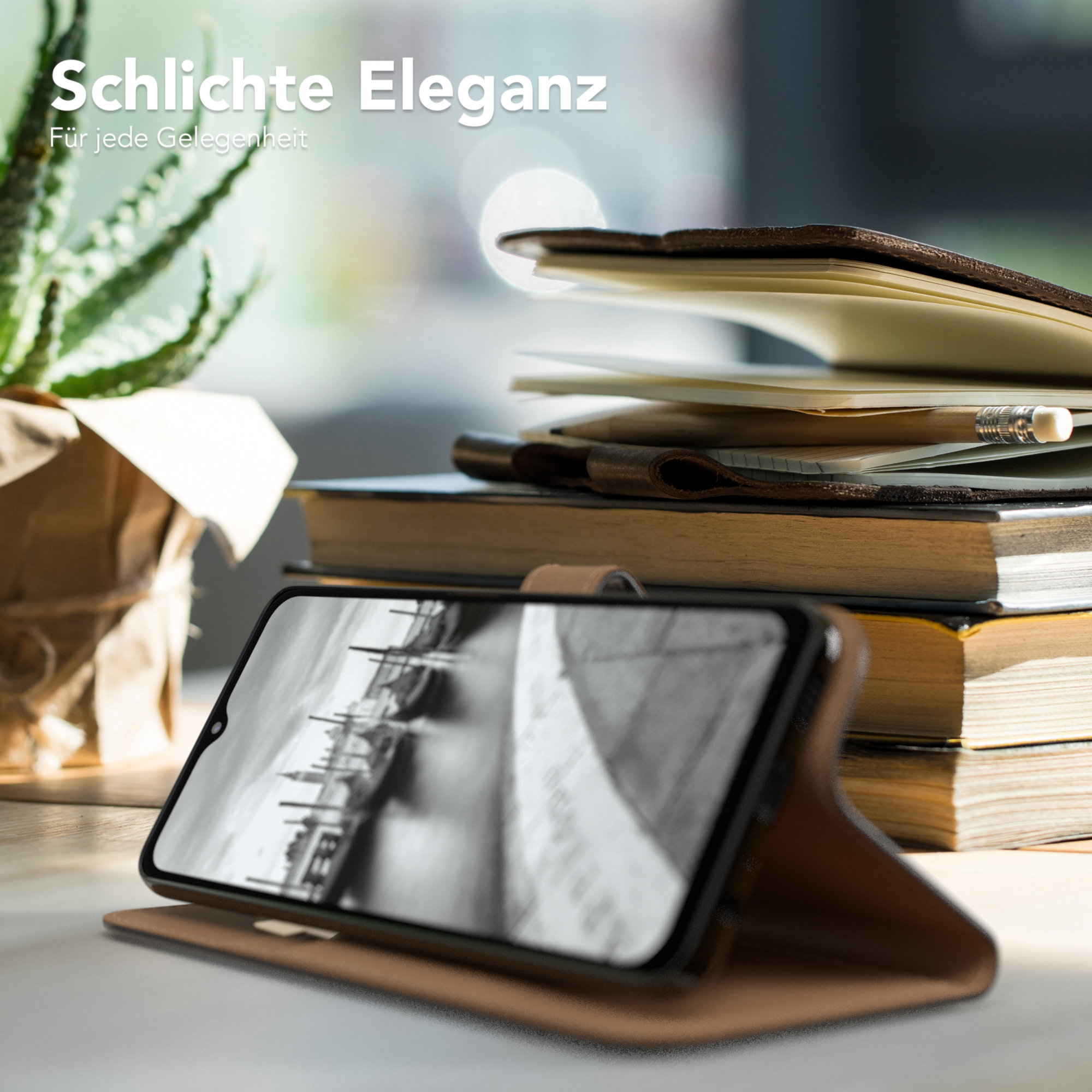 Ein Telefon in einer braunen Hülle ist auf einem Tisch geöffnet. Bücher, eine Pflanze und ein Bleistift liegen daneben.