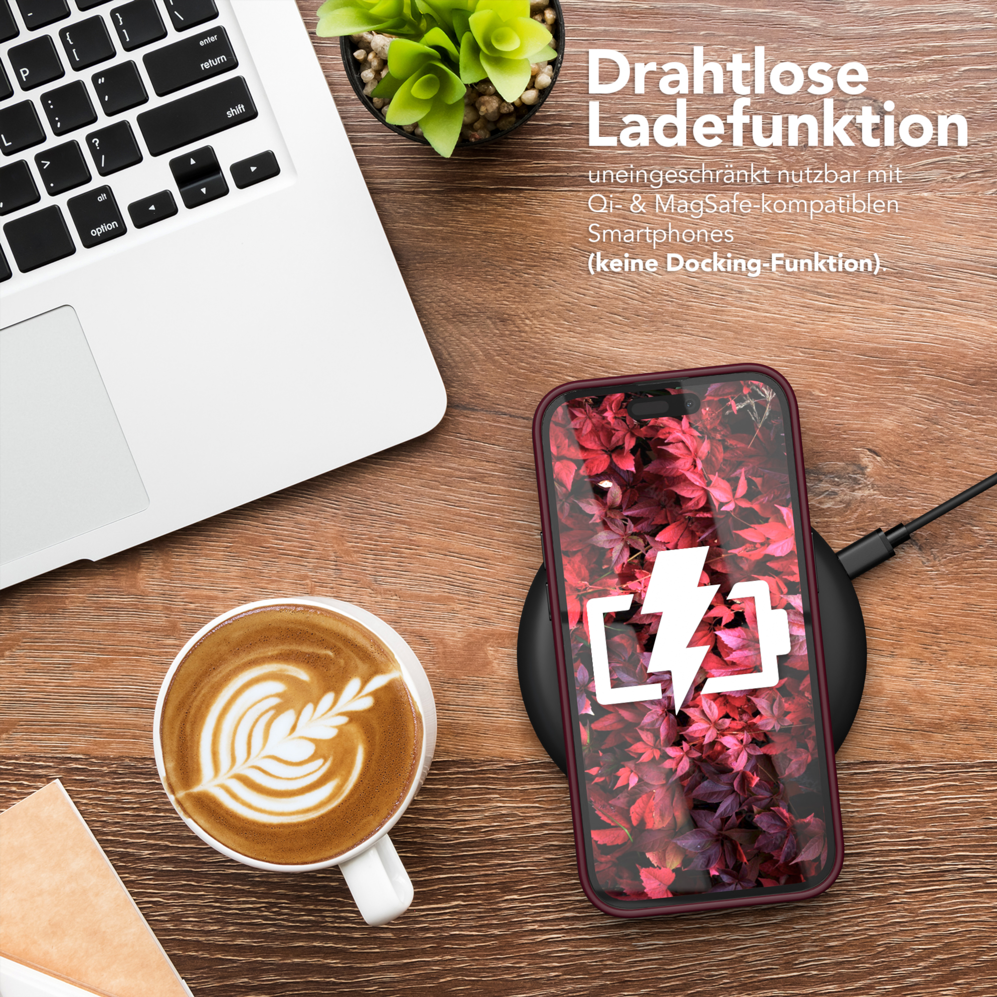 Ein Telefon wird kabellos geladen. Laptop und Kaffeetasse stehen auf dem Holztisch.