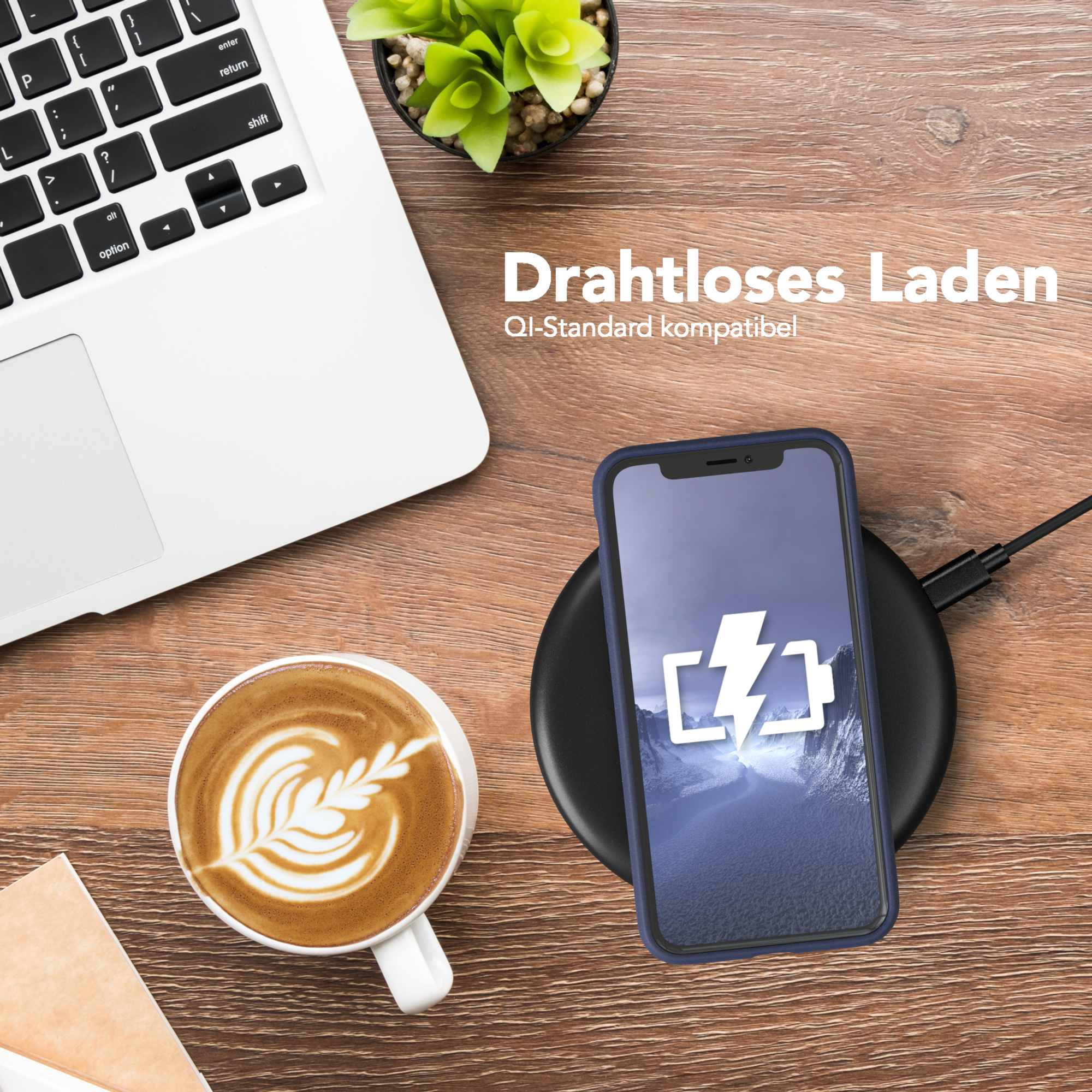 Laptop, Telefon auf kabellosem Ladegerät, Kaffee und eine kleine Pflanze auf Holzoberfläche.