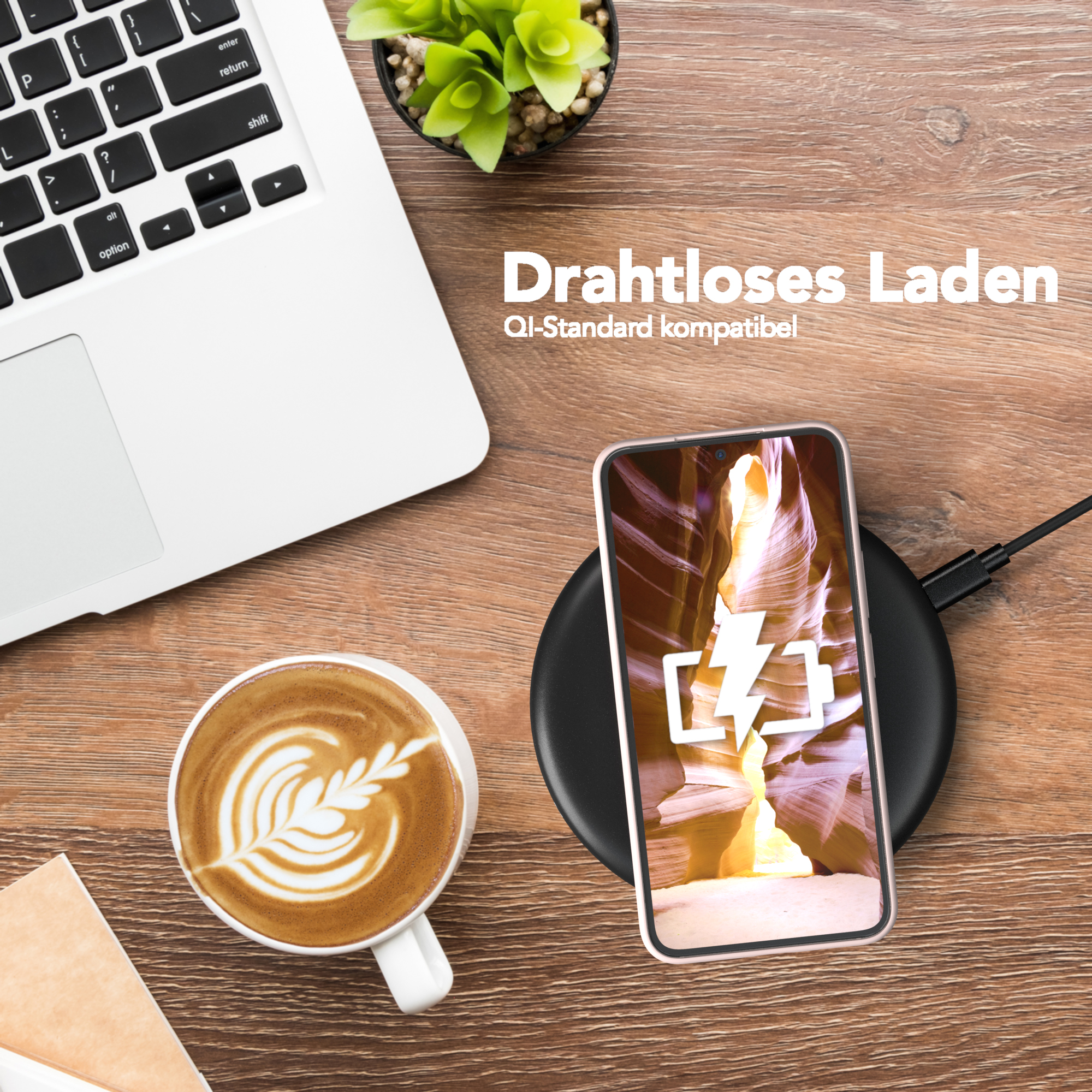 Ein Telefon in einer Hülle wird drahtlos auf einem Ladepad neben einer Tasse Kaffee und einem Laptop geladen.