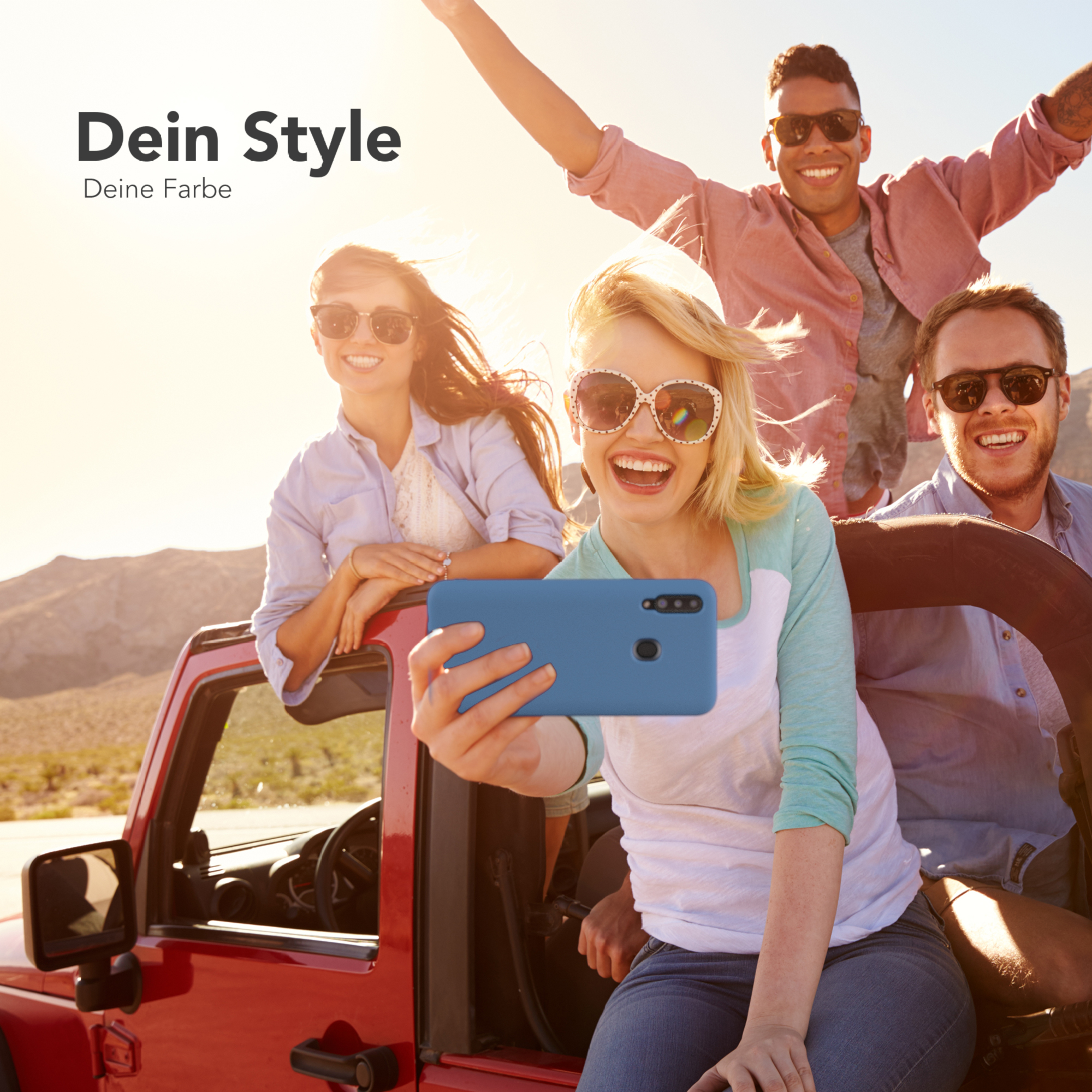Vier Personen in einem roten Jeep, eine Person hält ein Telefon mit blauer Hülle, lächelt und macht ein Selfie.