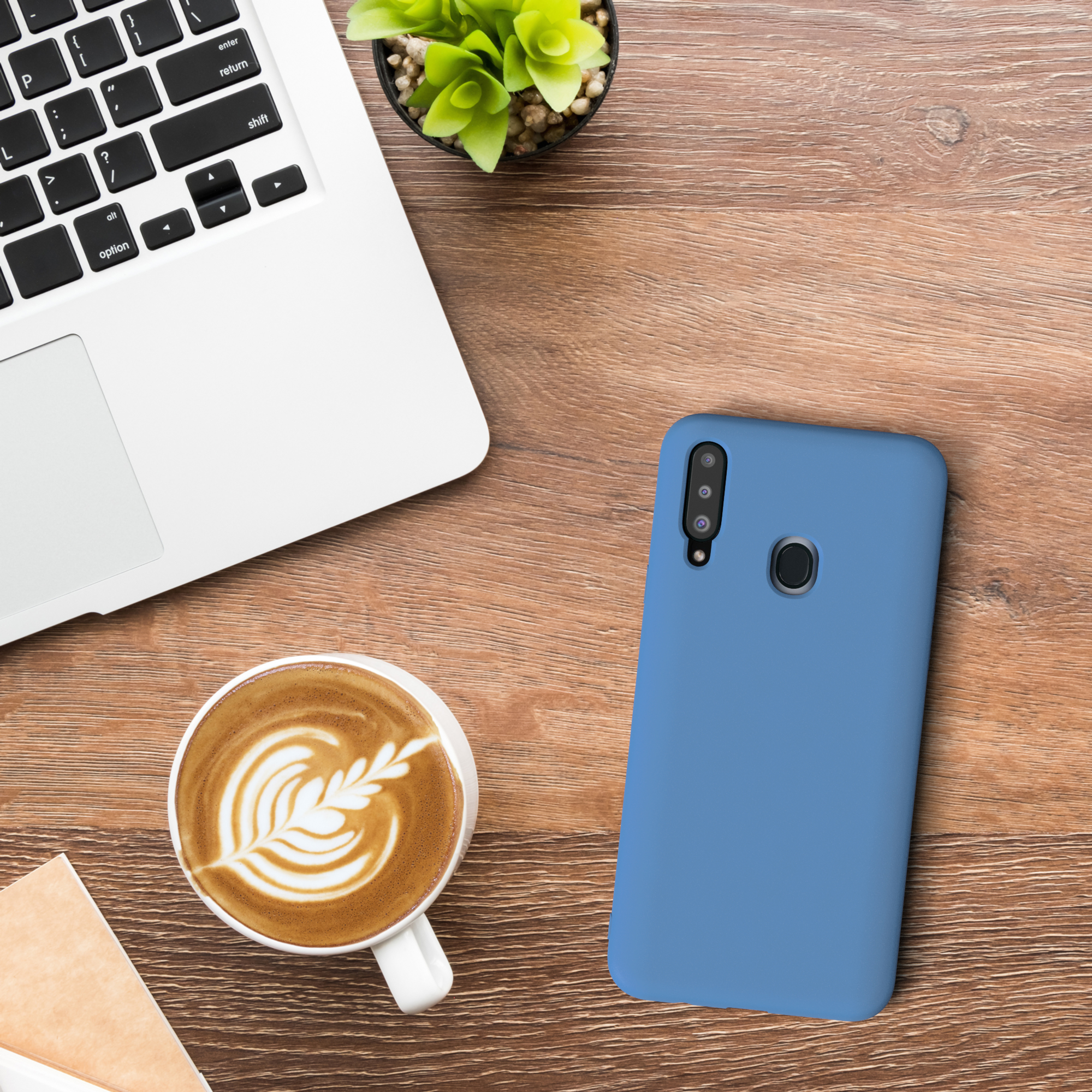 Laptop, Kaffee mit Latte Art, blaue Handyhülle und eine kleine Pflanze auf Holz.