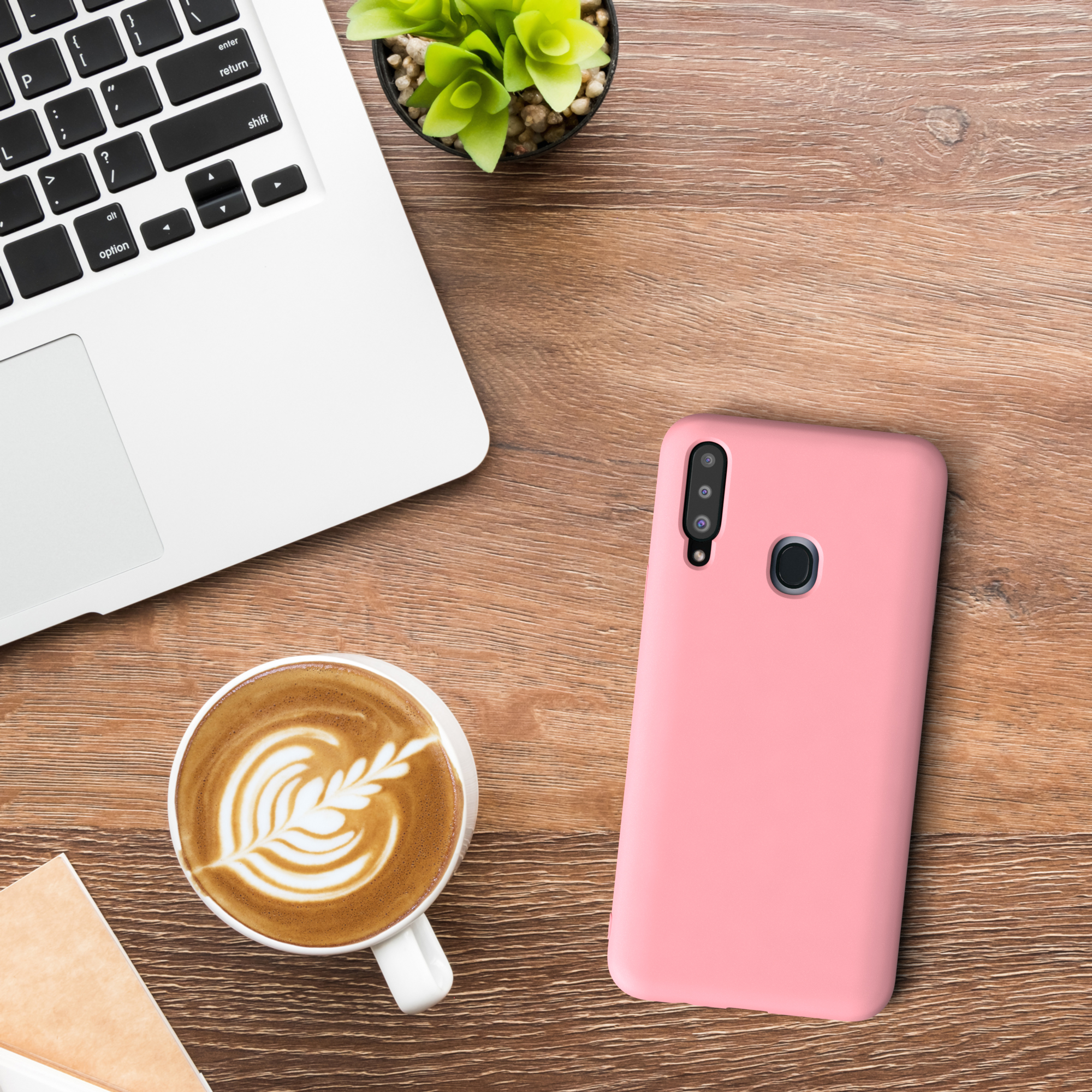 Ein Laptop, eine Kaffeetasse mit Latte Art, ein Telefon und eine kleine Pflanze auf Holztisch.