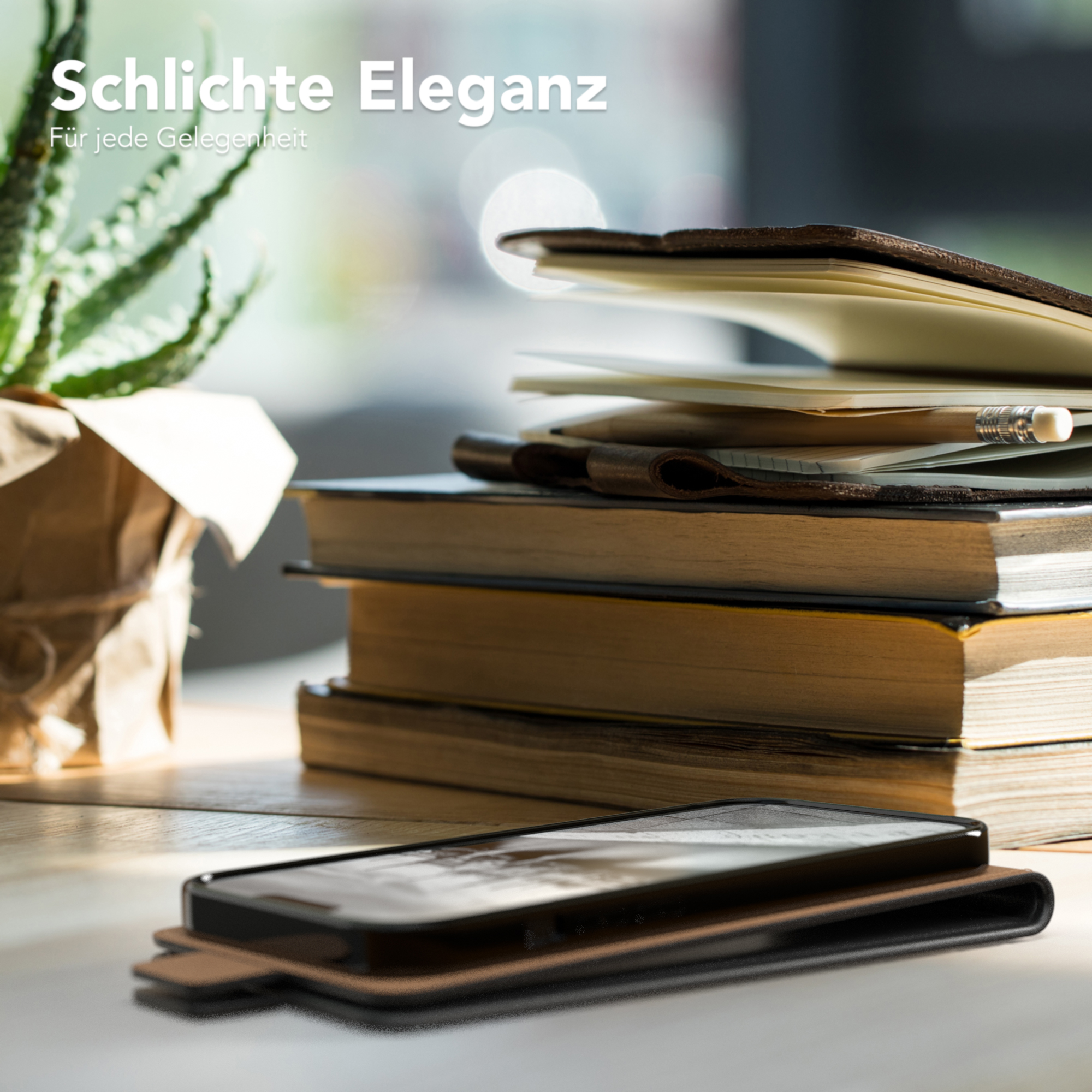 Handyhülle liegt auf einem Holztisch neben Büchern und einer Pflanze. Zeigt schlichtes Design.