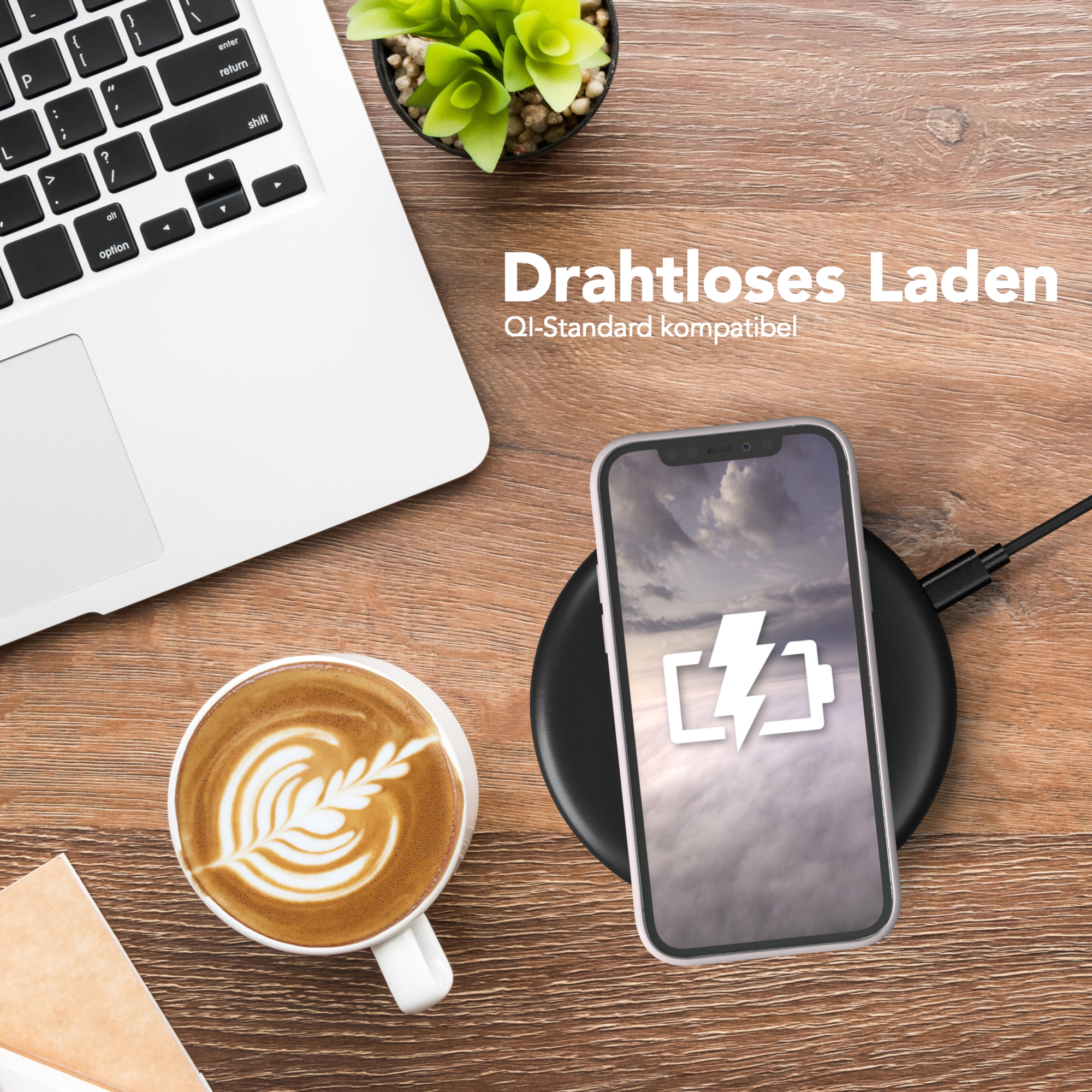 Ein Telefon, das auf einem kabellosen Ladegerät geladen wird. Eine Tasse Kaffee und ein Laptop sind sichtbar.