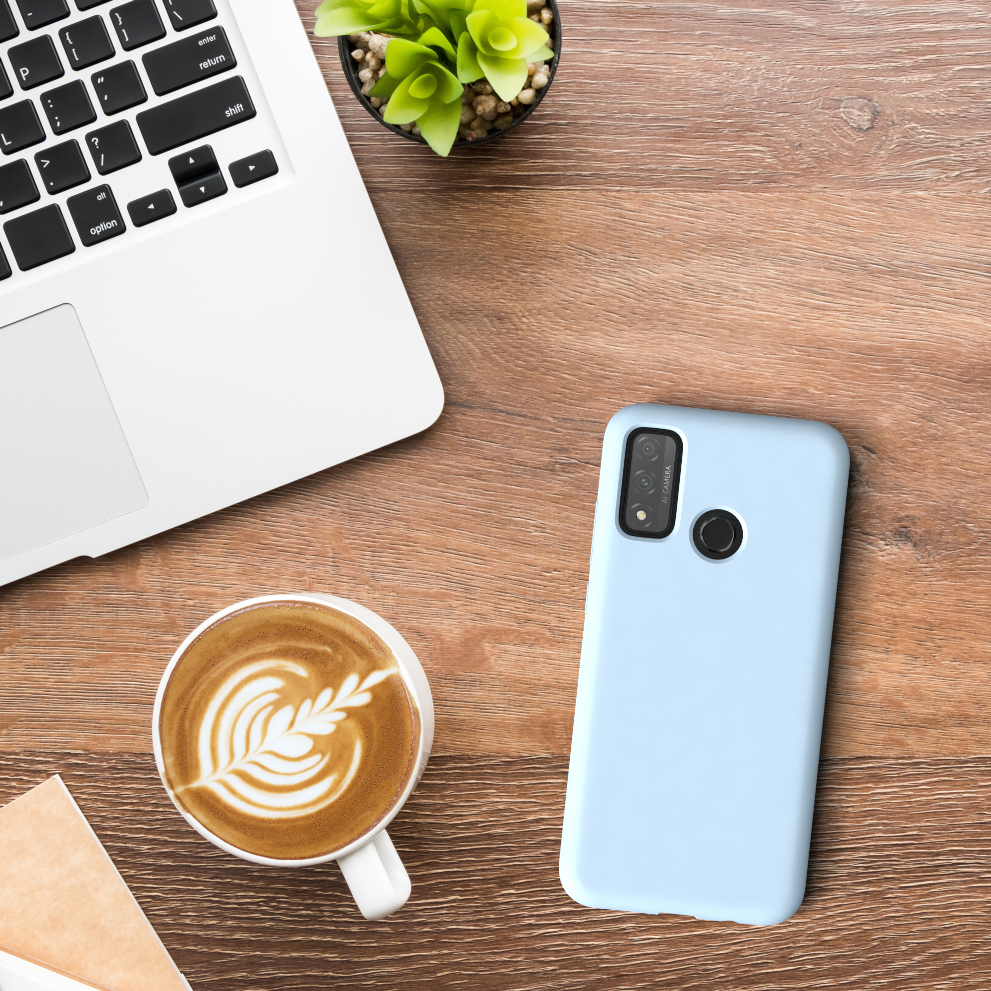 Ein Laptop, eine Kaffeetasse mit Latte Art, eine Handyhülle und eine Pflanze auf einem Holztisch.
