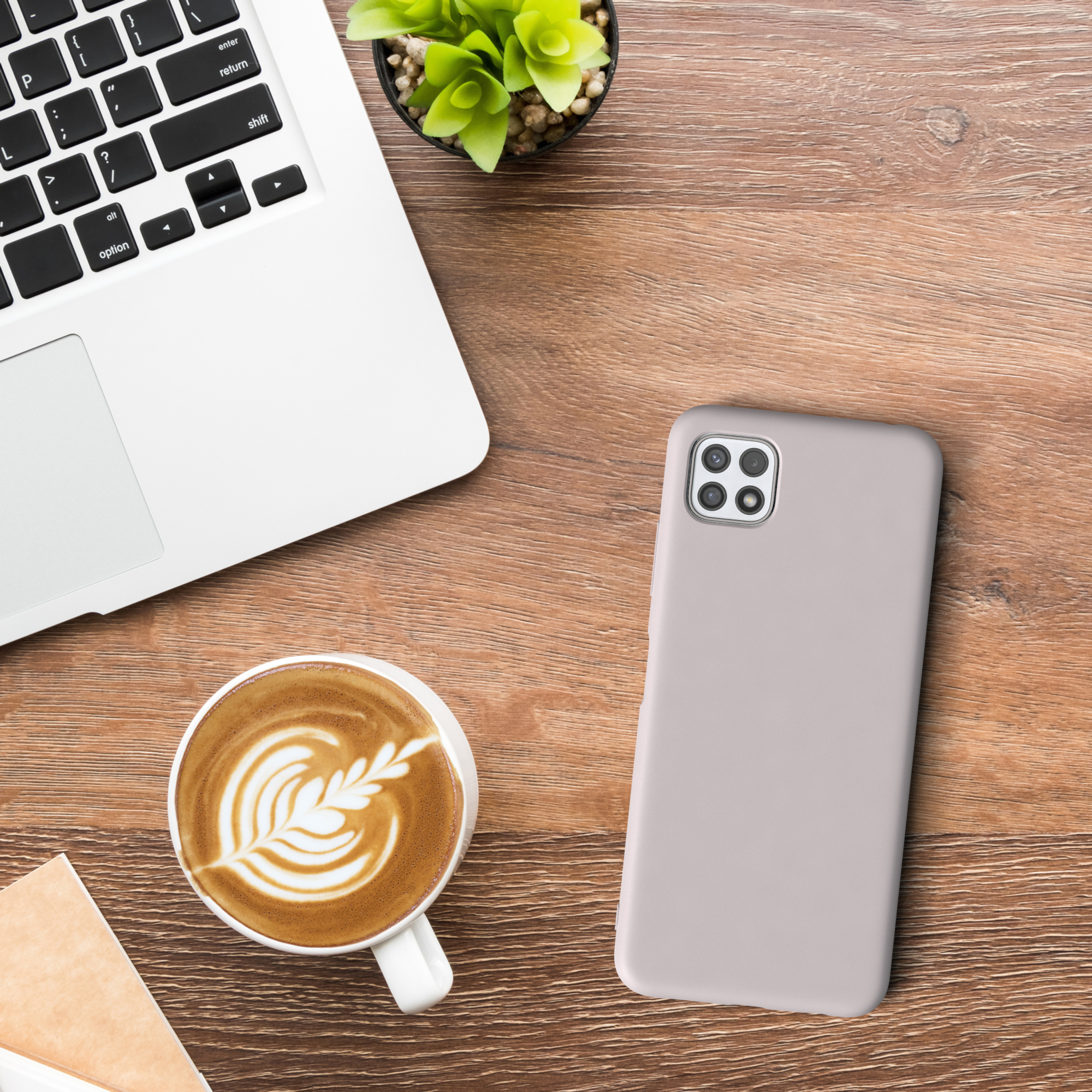 Laptop, Kaffee mit Latte Art und ein Telefon auf einer Holzoberfläche.