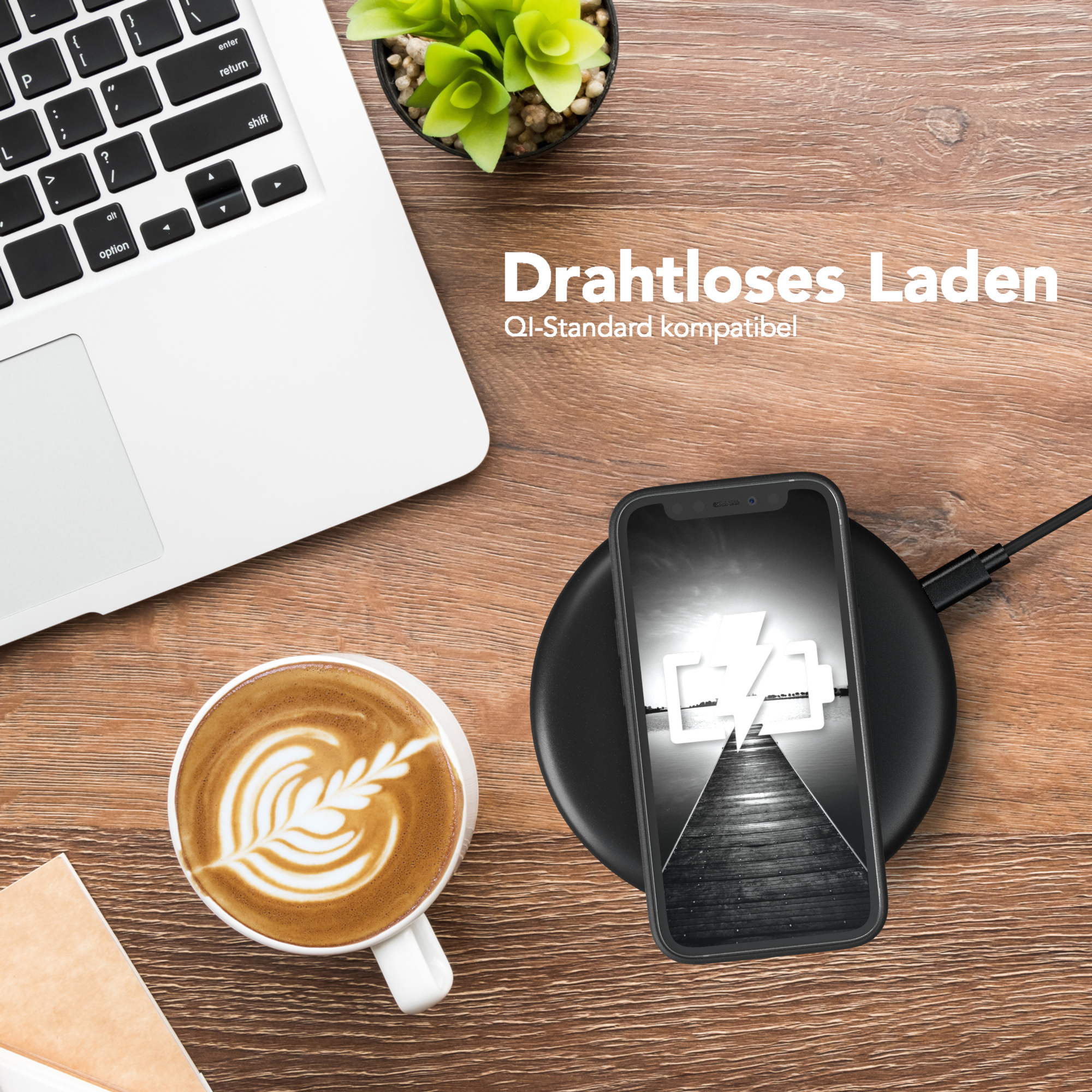 Telefon wird auf kabellosem Ladegerät aufgeladen. Laptop, Kaffee und Pflanze auf Holzschreibtisch.