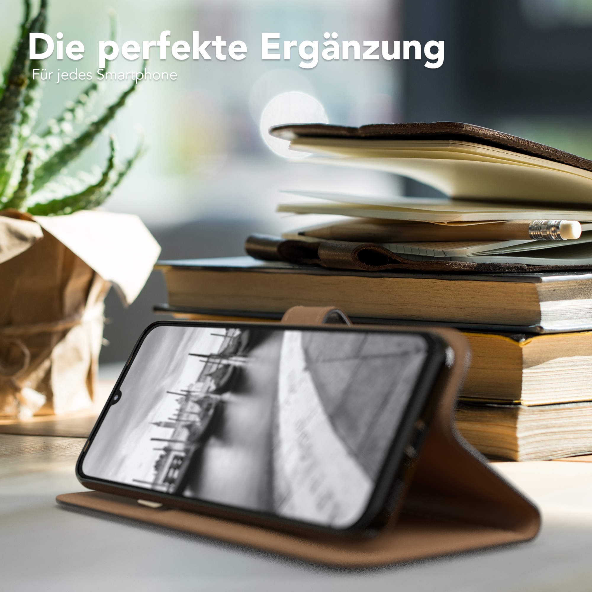 Telefon in brauner Hülle auf Schreibtisch mit Büchern und Pflanze im Hintergrund, mit Text.