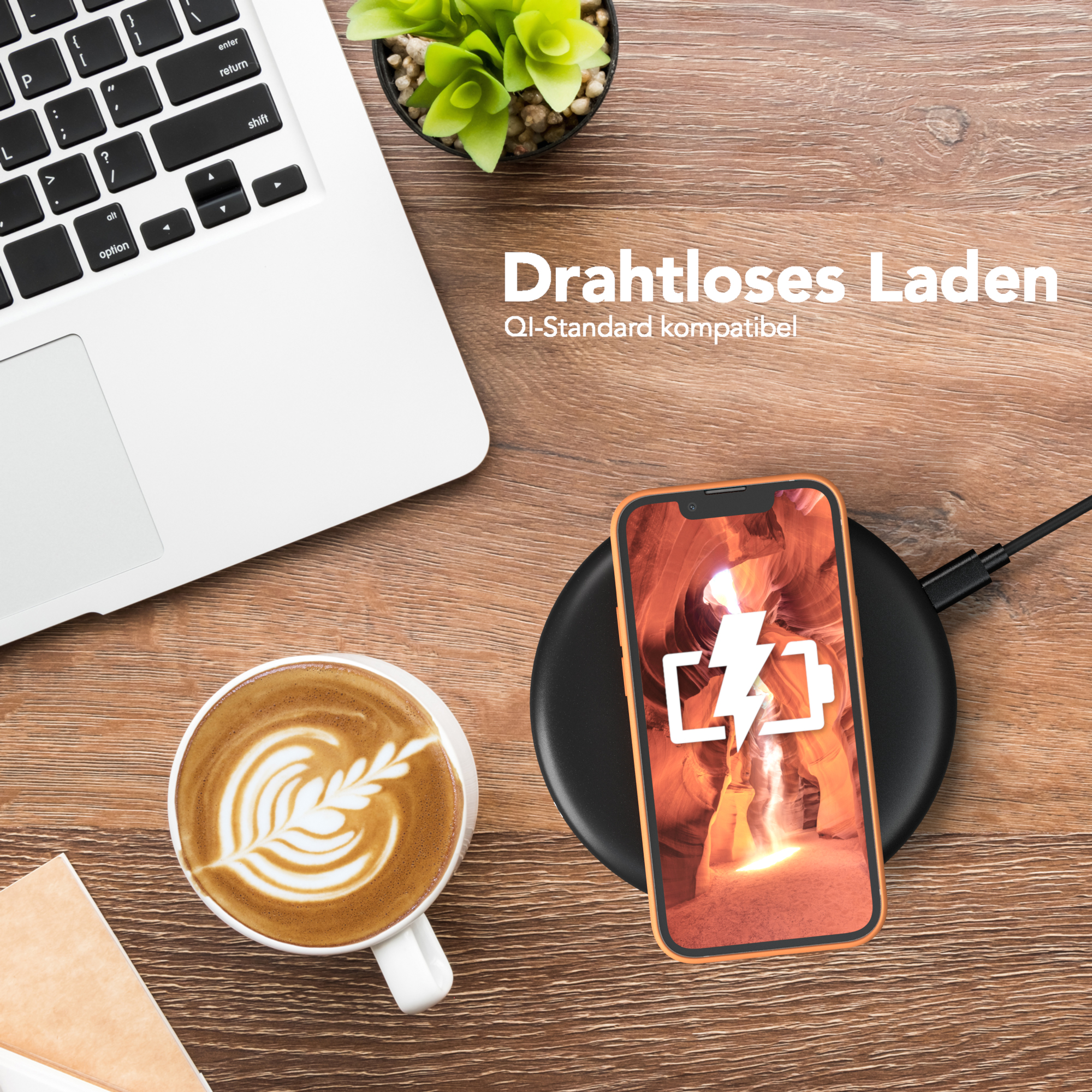 Telefon auf kabellosem Ladegerät neben Laptop, Kaffee mit Kunst.
