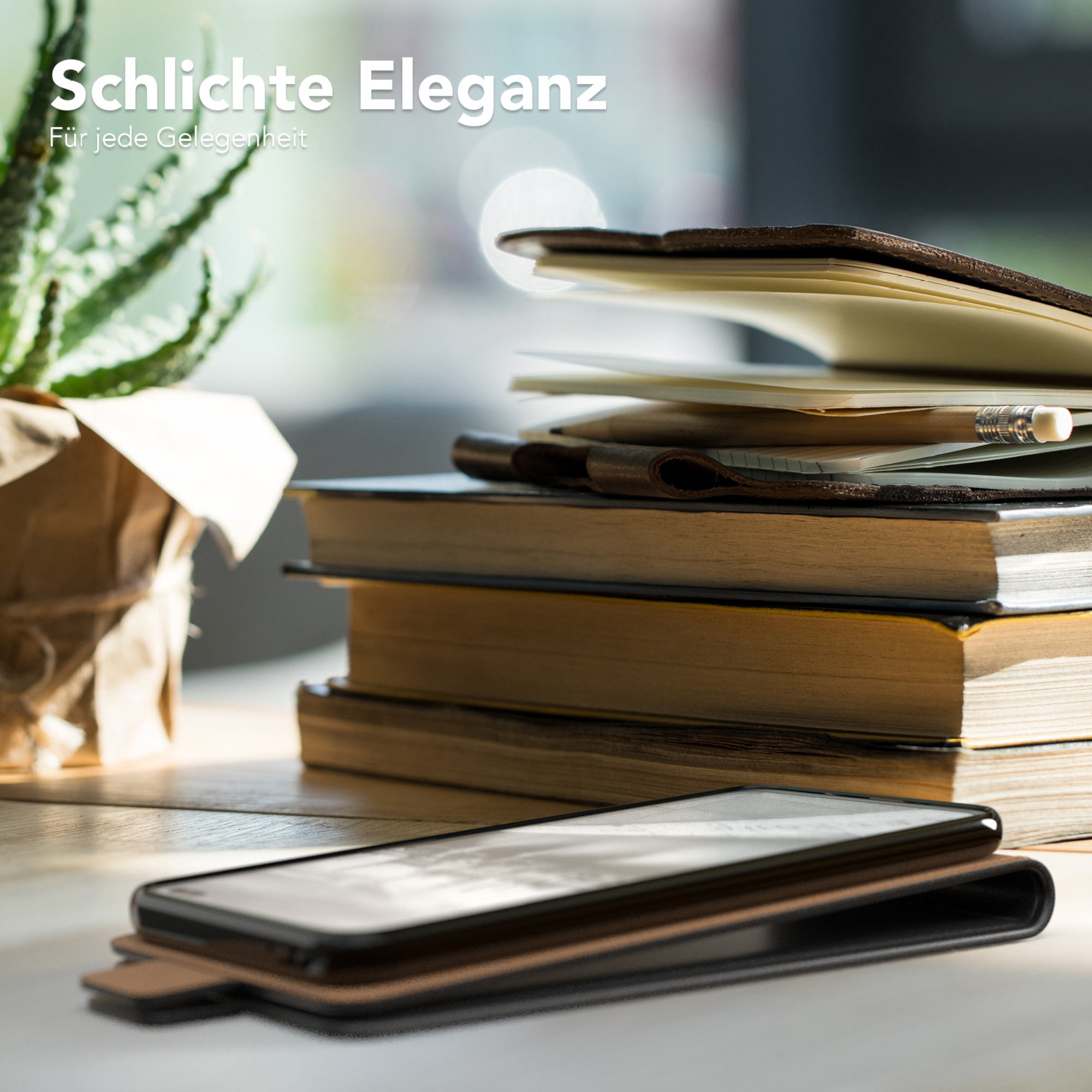 Telefon in einer Lederhülle, Bücher und Pflanze auf einem Holztisch.