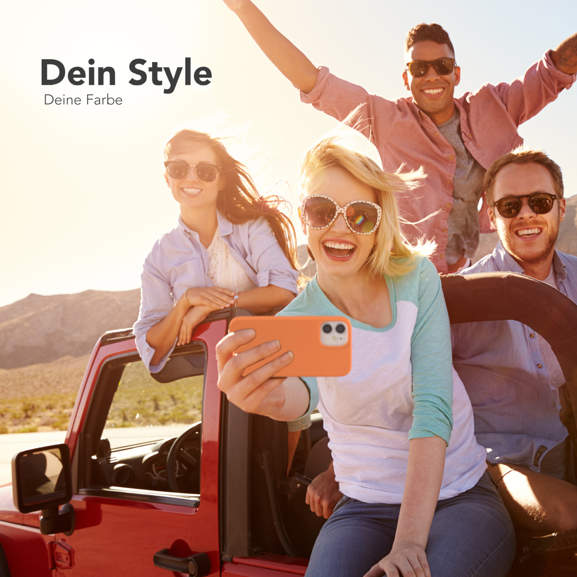 Vier Personen machen ein Selfie in einem roten Jeep, fröhliche Gesichter, sonniger Tag.