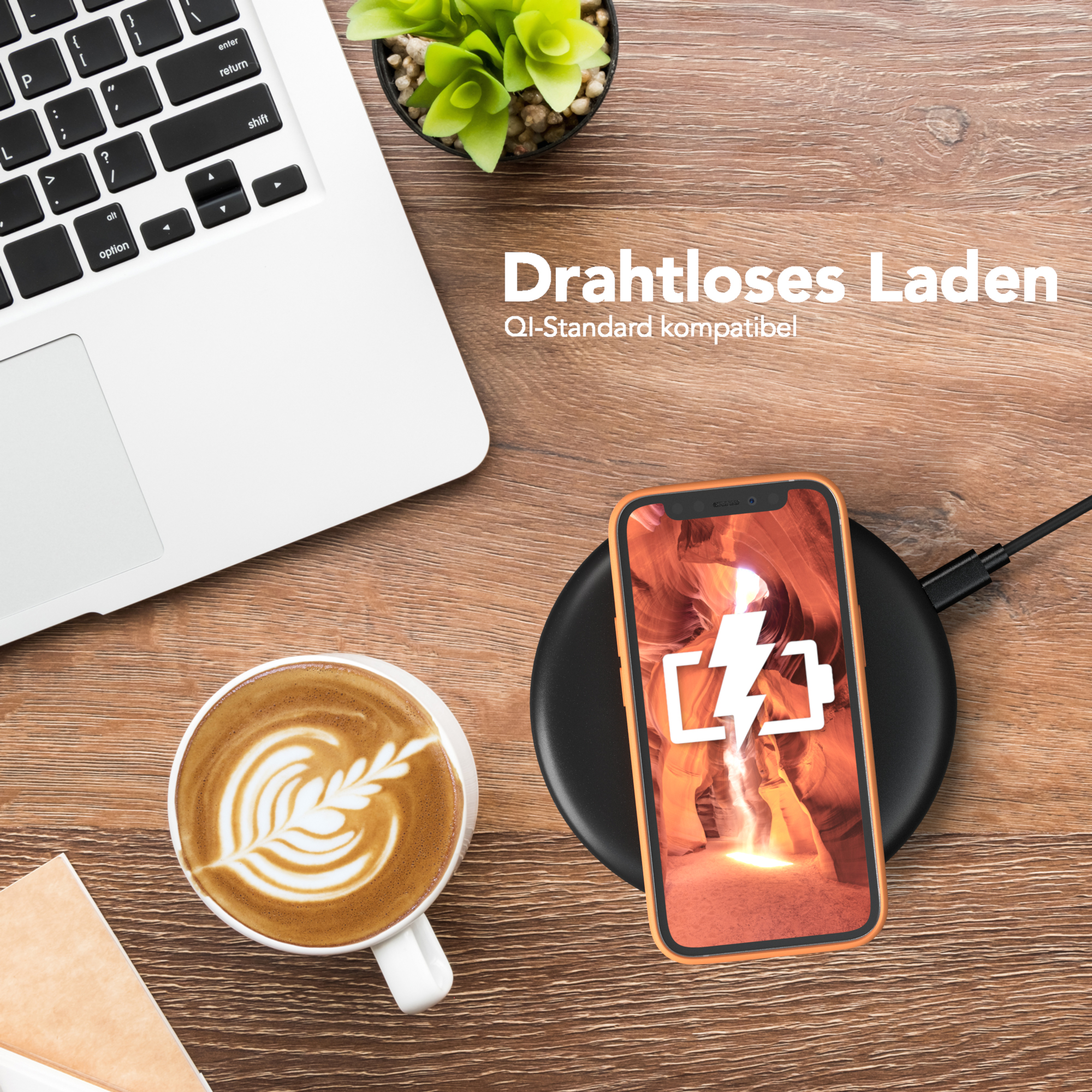 Kabelloses Ladegerät mit Telefon und Hülle. Latte Art Kaffee und Laptop auf Holzschreibtisch.