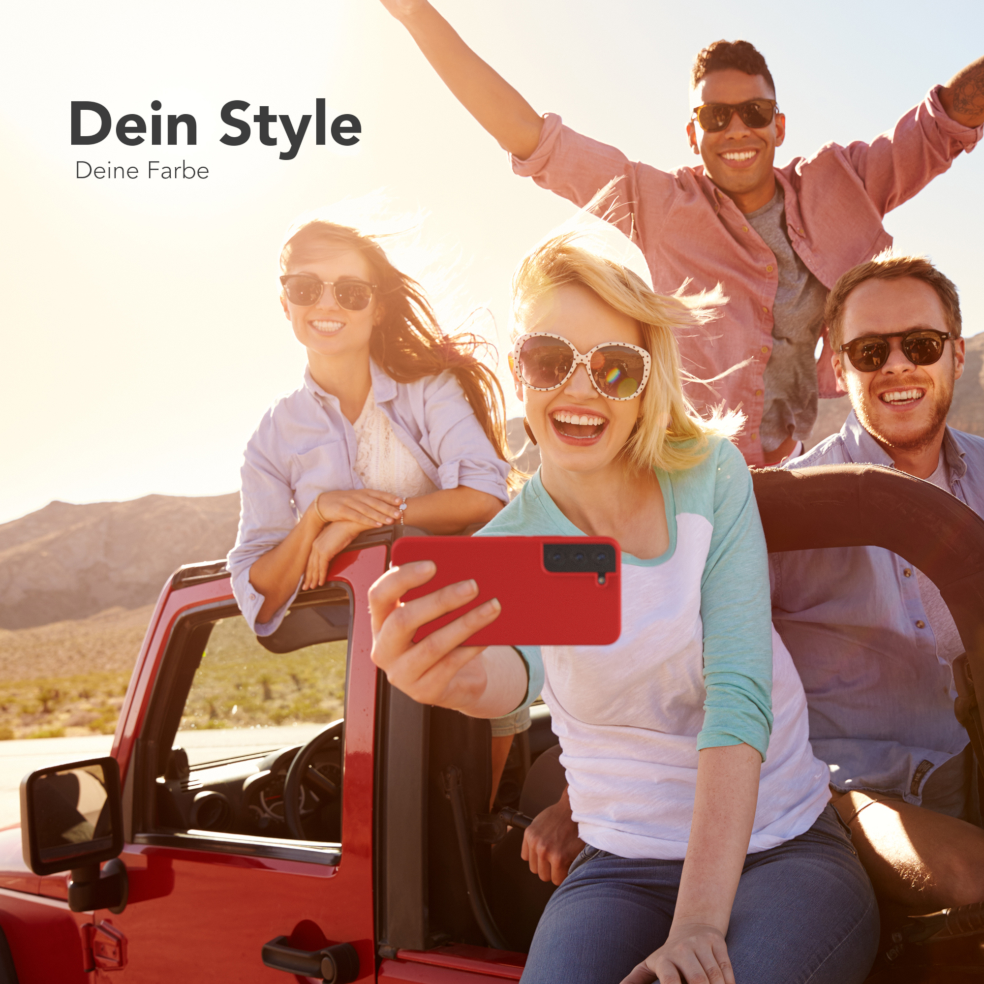 Vier lächelnde Personen posieren für ein Selfie vor einem roten Jeep. Einer hält eine rote Handyhülle.