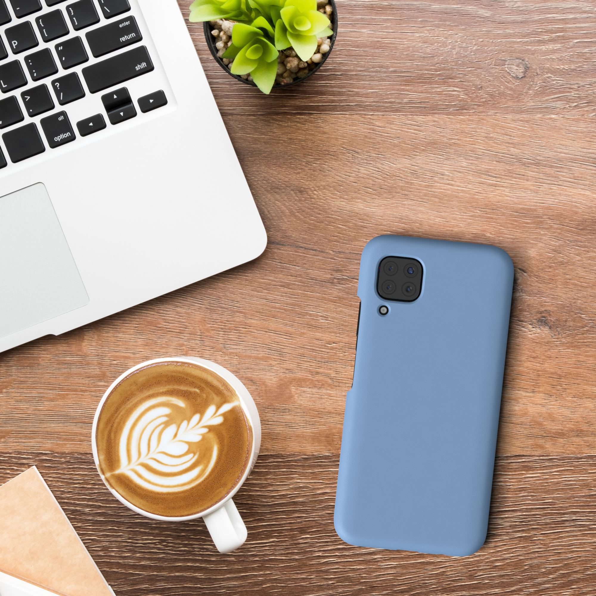 Laptop, Kaffee, Telefon in blauer Hülle und Pflanze auf einem Holztisch.