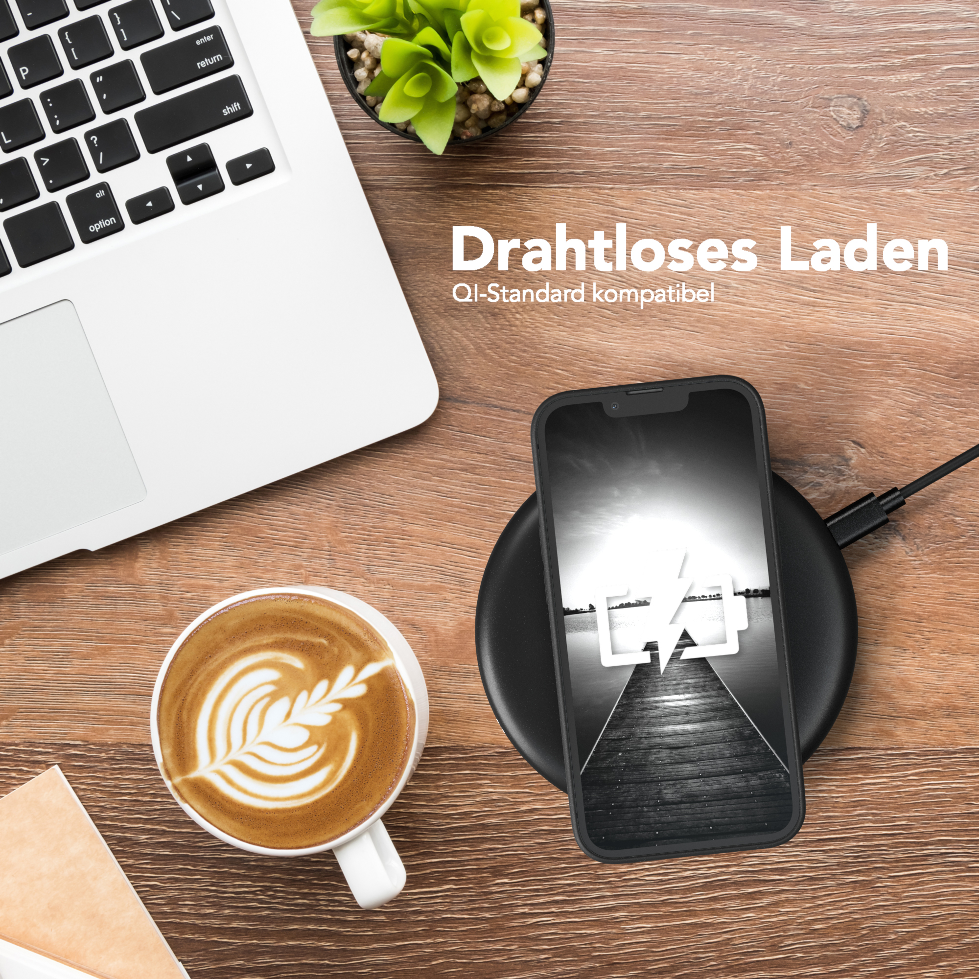 Telefon wird geladen. Laptop, Kaffeetasse mit Kunst und kleine Pflanze auf dem Holztisch.