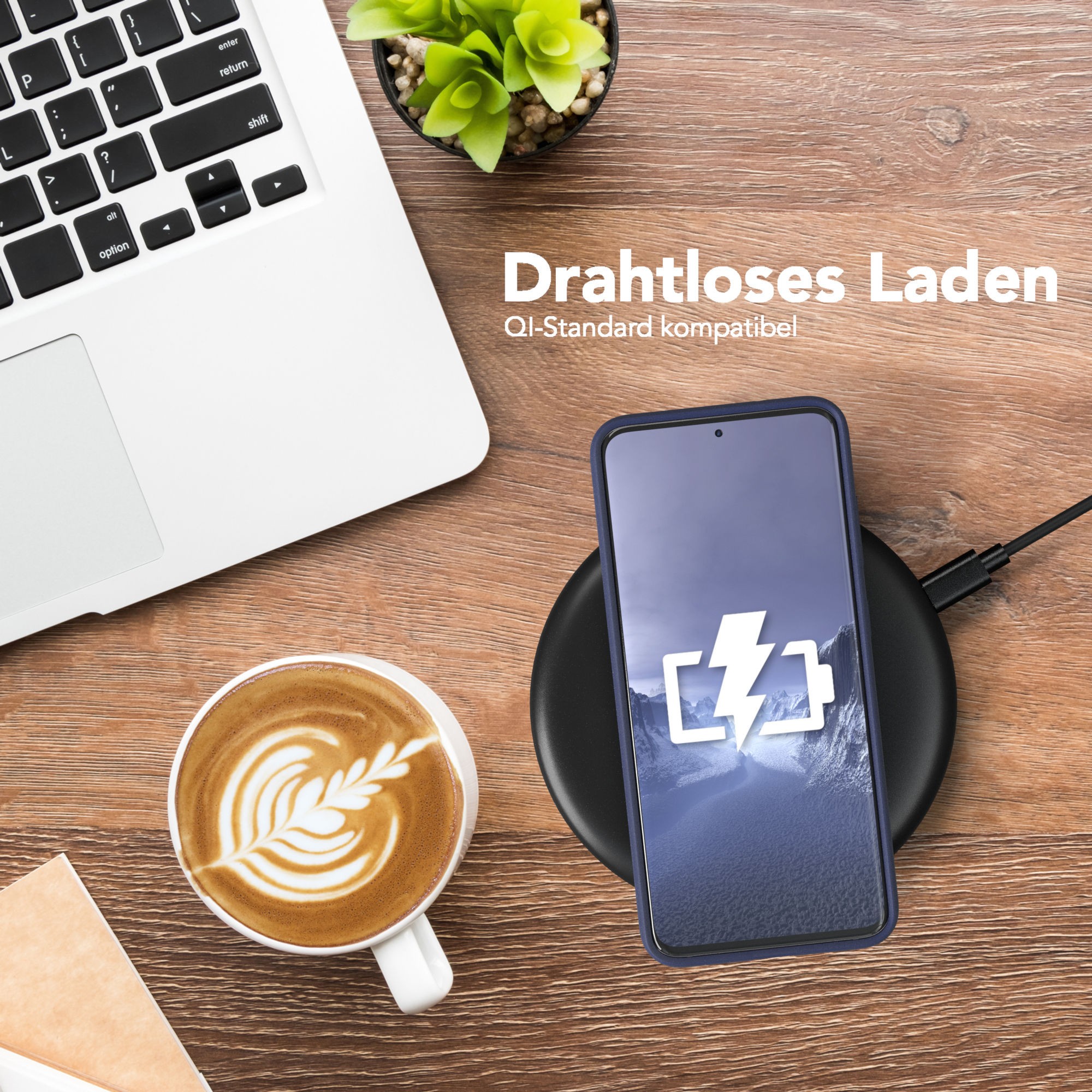 Telefon wird kabellos auf einem schwarzen Pad geladen, neben Laptop und Kaffeetasse.