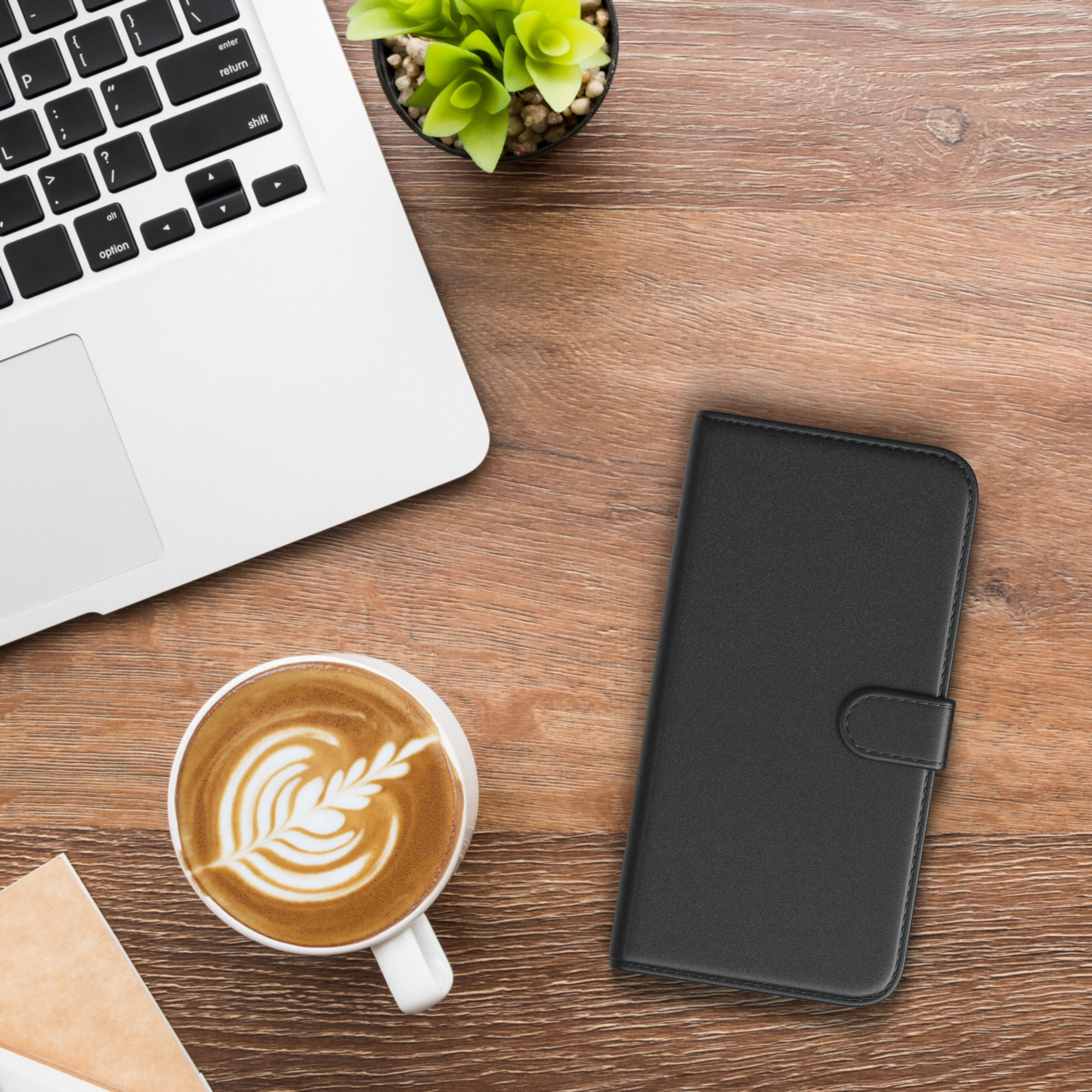 Ein Laptop, Kaffee und eine Handyhülle auf einem Holztisch.