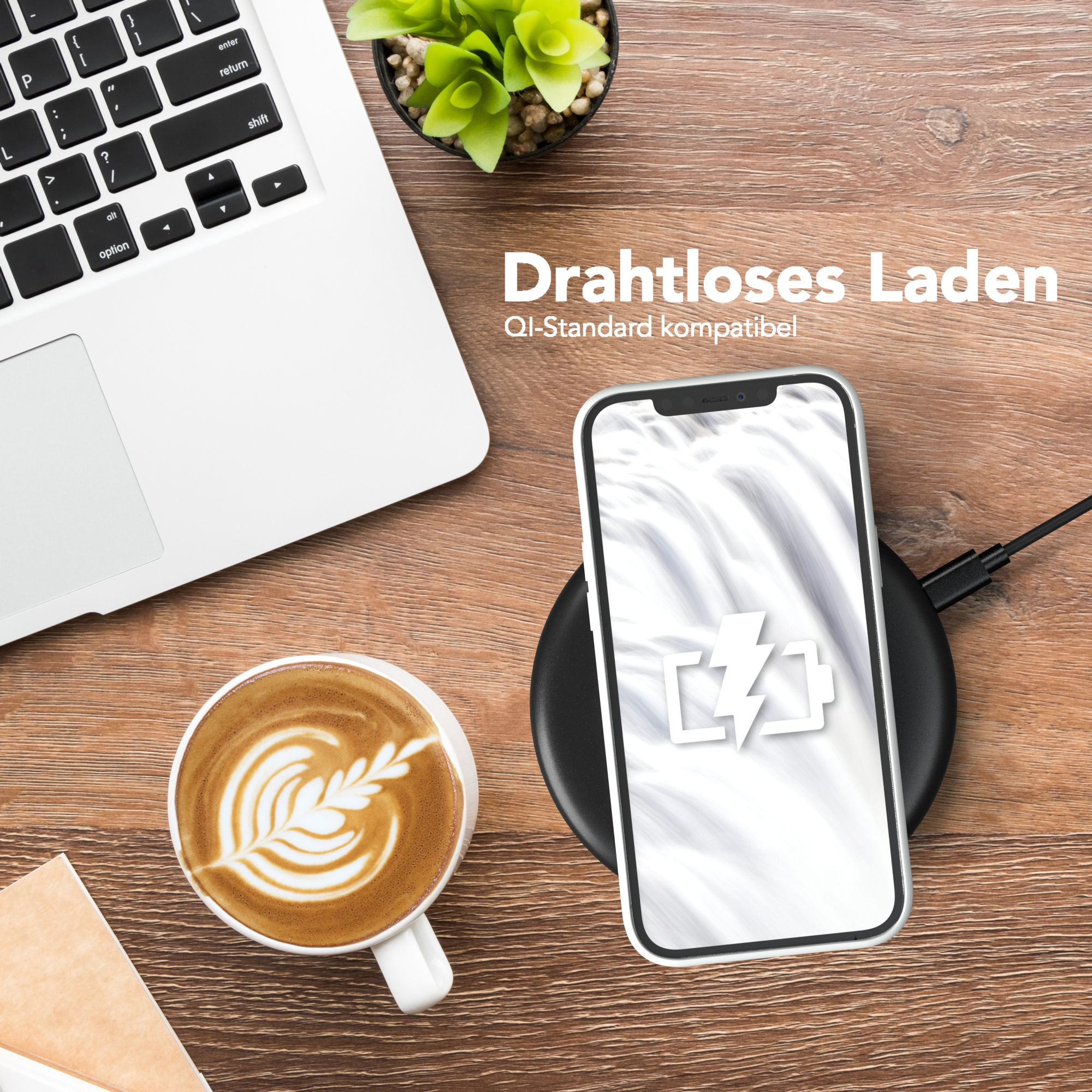 Ein Telefon auf einem kabellosen Ladegerät. Eine Kaffeetasse mit Latte Art und ein Laptop sind sichtbar.