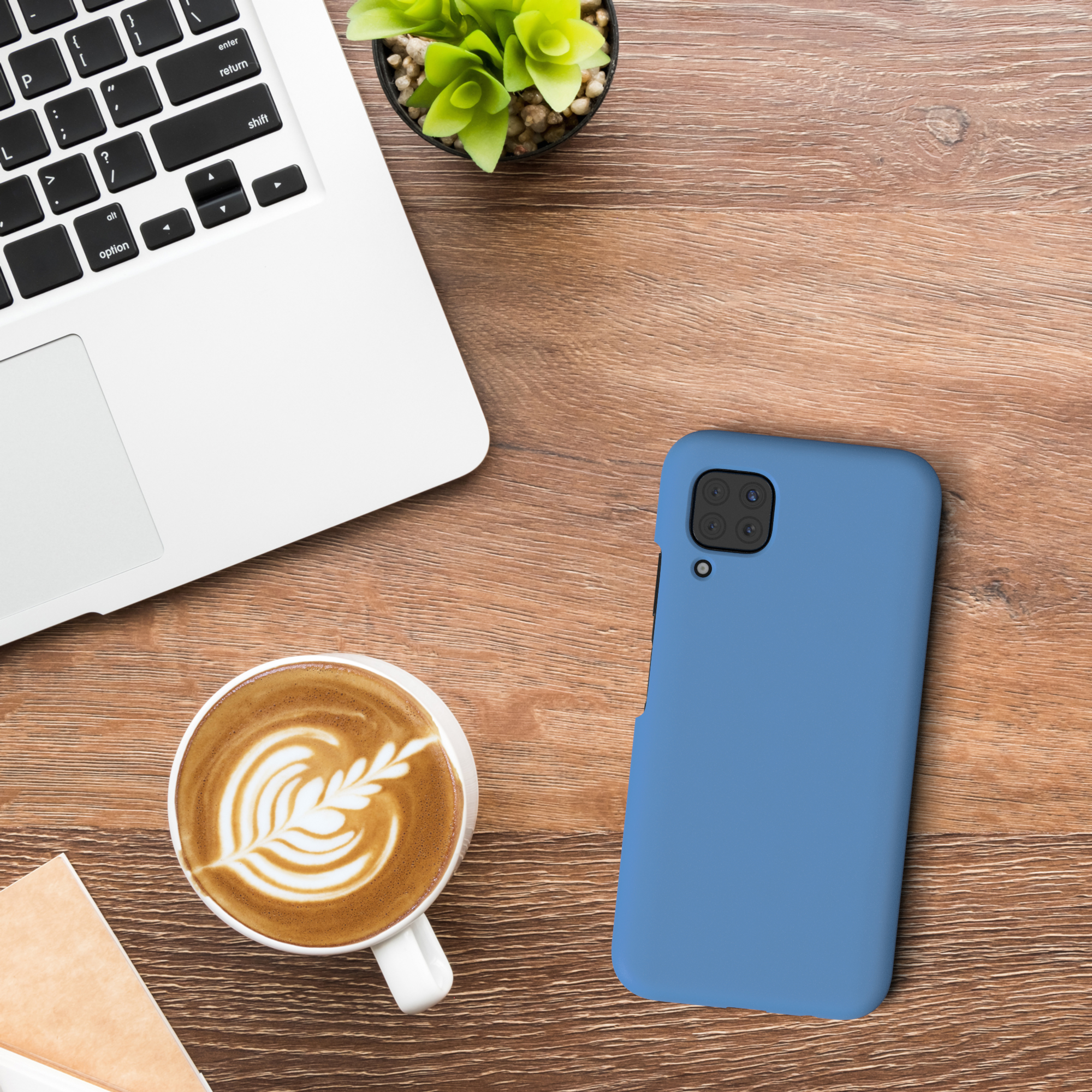 Blaue Handyhülle auf einem Holztisch. Daneben ein Laptop und ein Kaffee mit Latte Art.