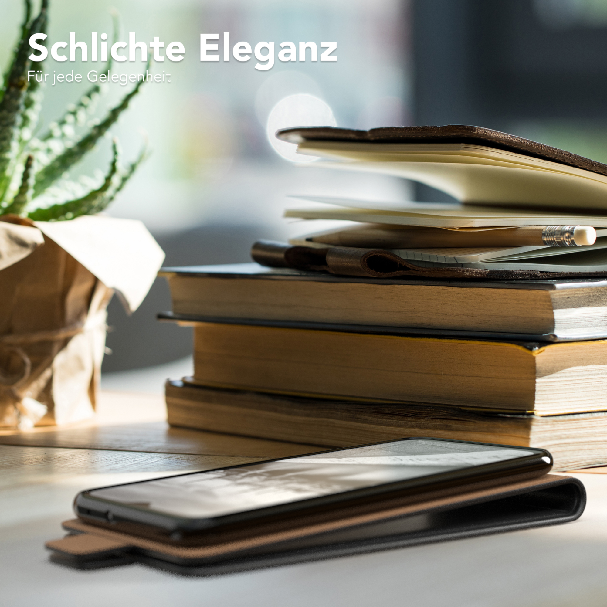Telefon in einer braunen Hülle auf einem Tisch mit Büchern und einer Pflanze. Natürliches Licht.