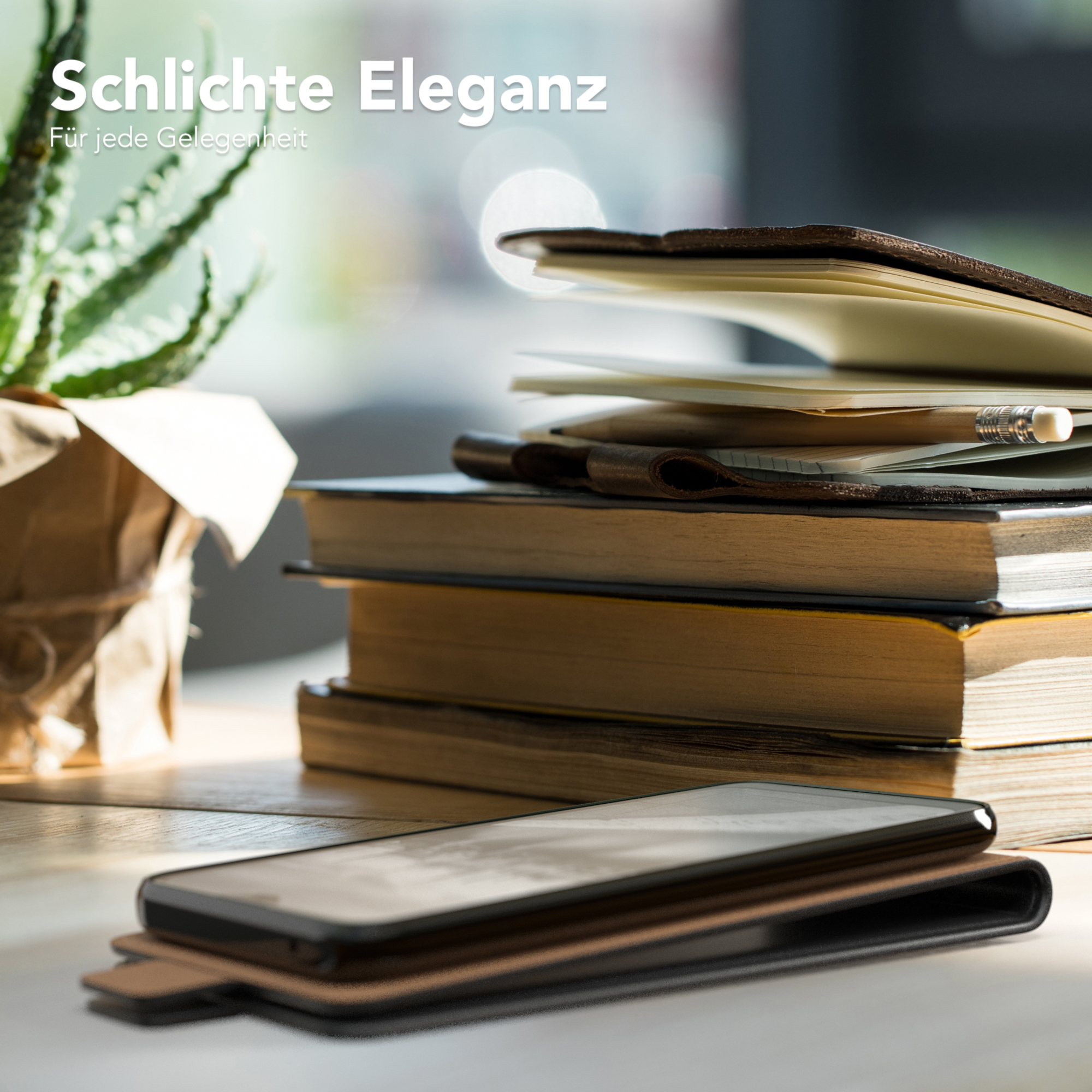 Telefon auf Tisch mit Büchern. Telefon ist in Hülle. Pflanze im Hintergrund, natürliches Licht.