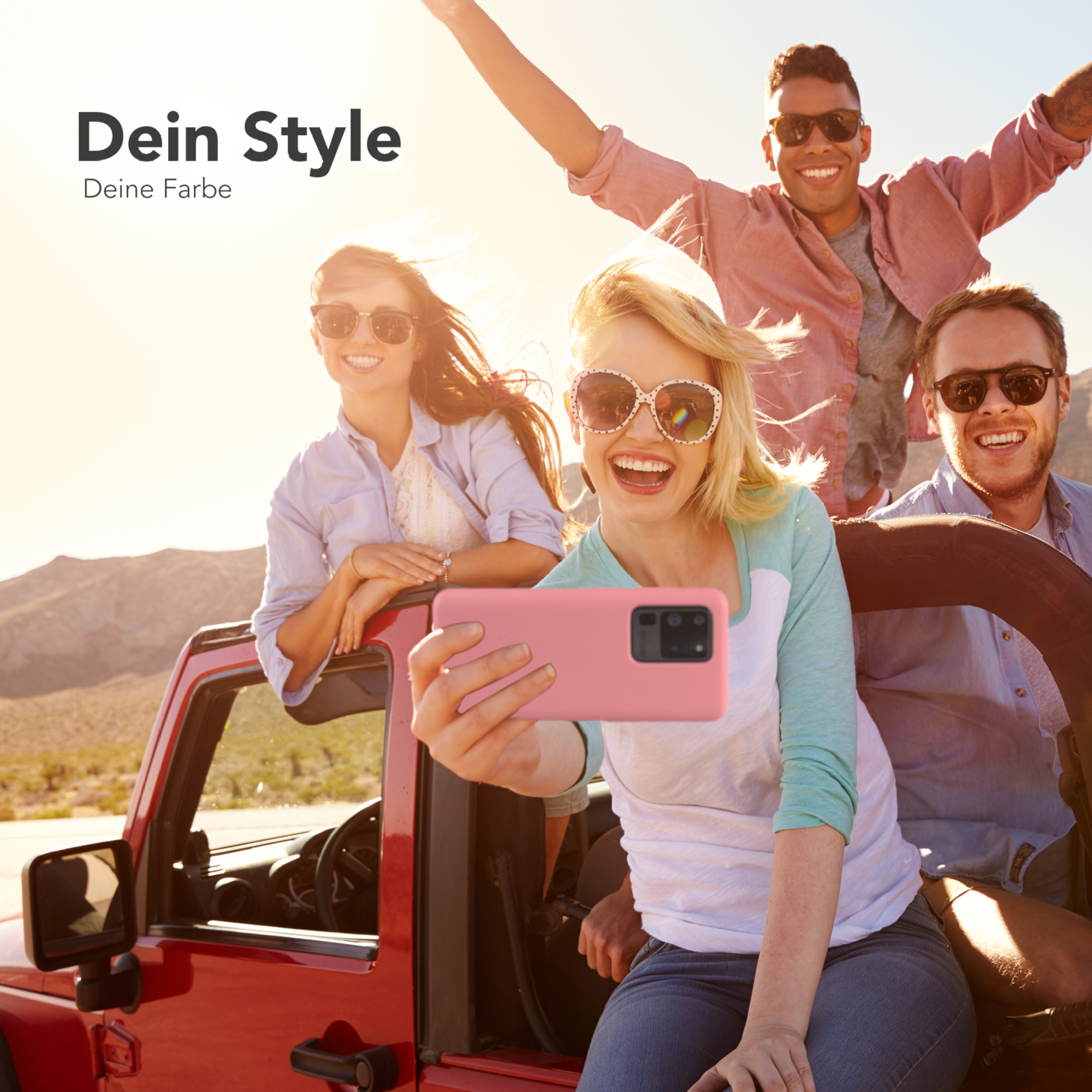 Vier Personen in einem roten Auto, die lächeln und ein Selfie machen, mit Bergkulisse.