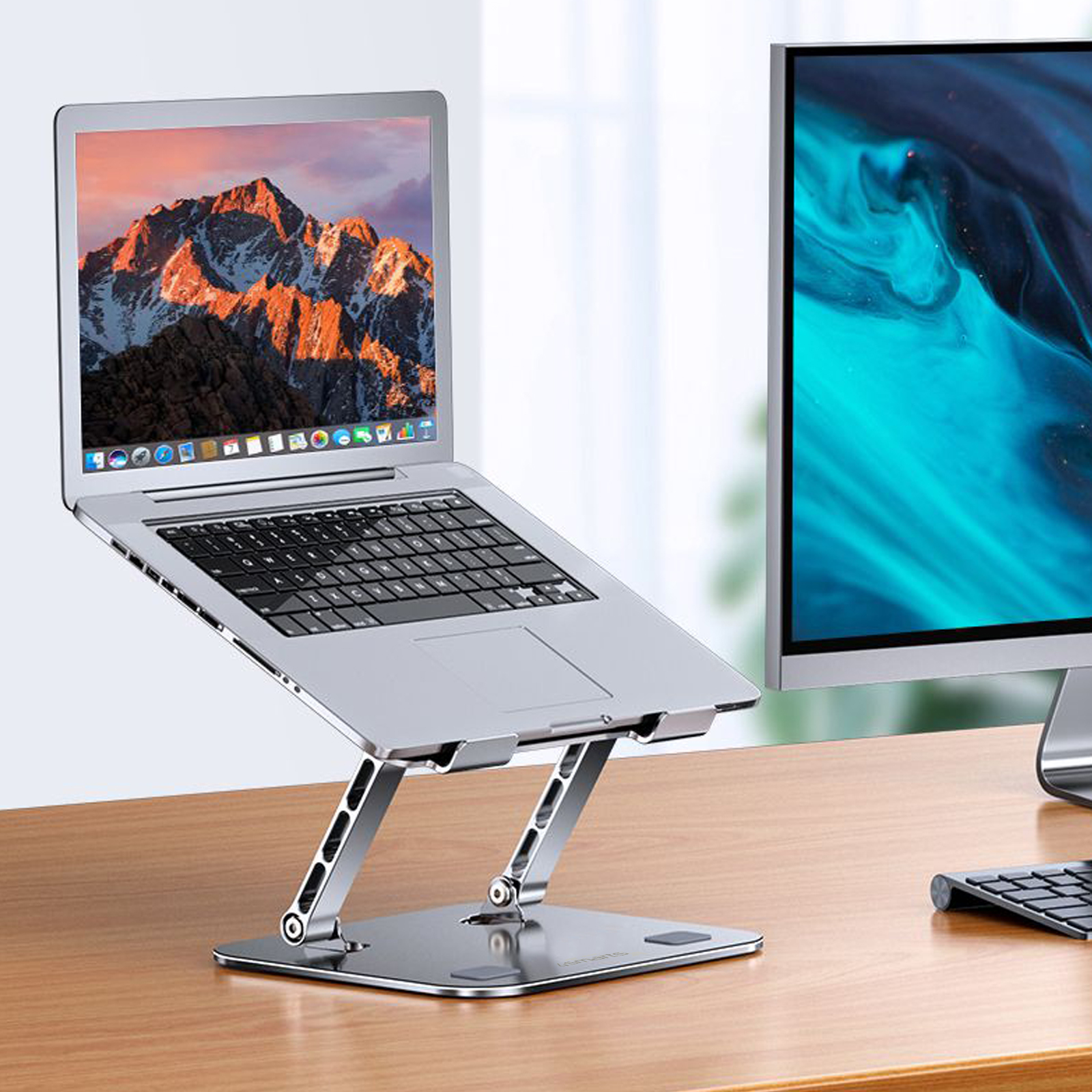 Laptop auf silbernem Ständer, Bergdisplay und Monitor. Holzschreibtisch.