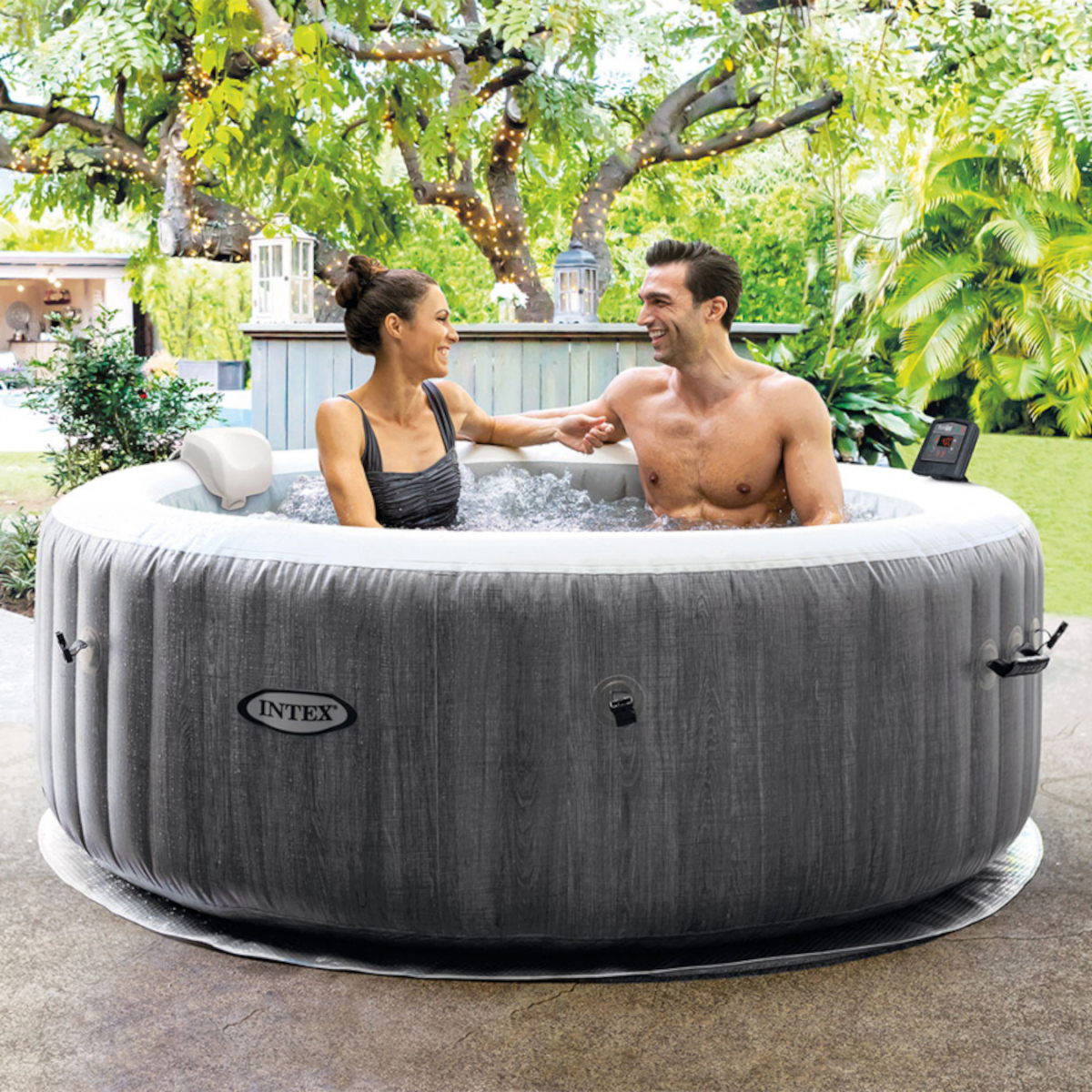 Ein Paar ist draußen in einem Whirlpool. Sie lächeln.
