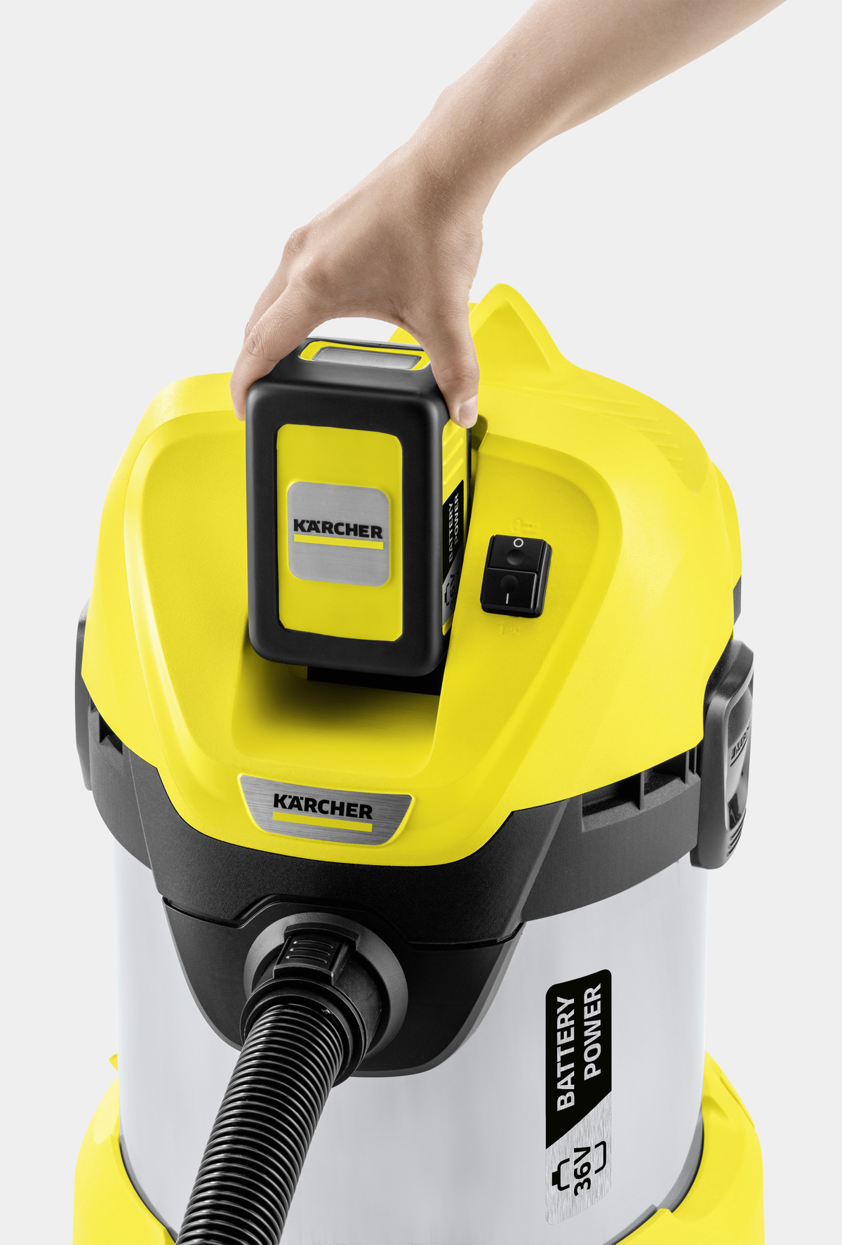 Una persona tiene in mano un aspirapolvere giallo e nero, inserendo una batteria. Il logo Kärcher è visibile.