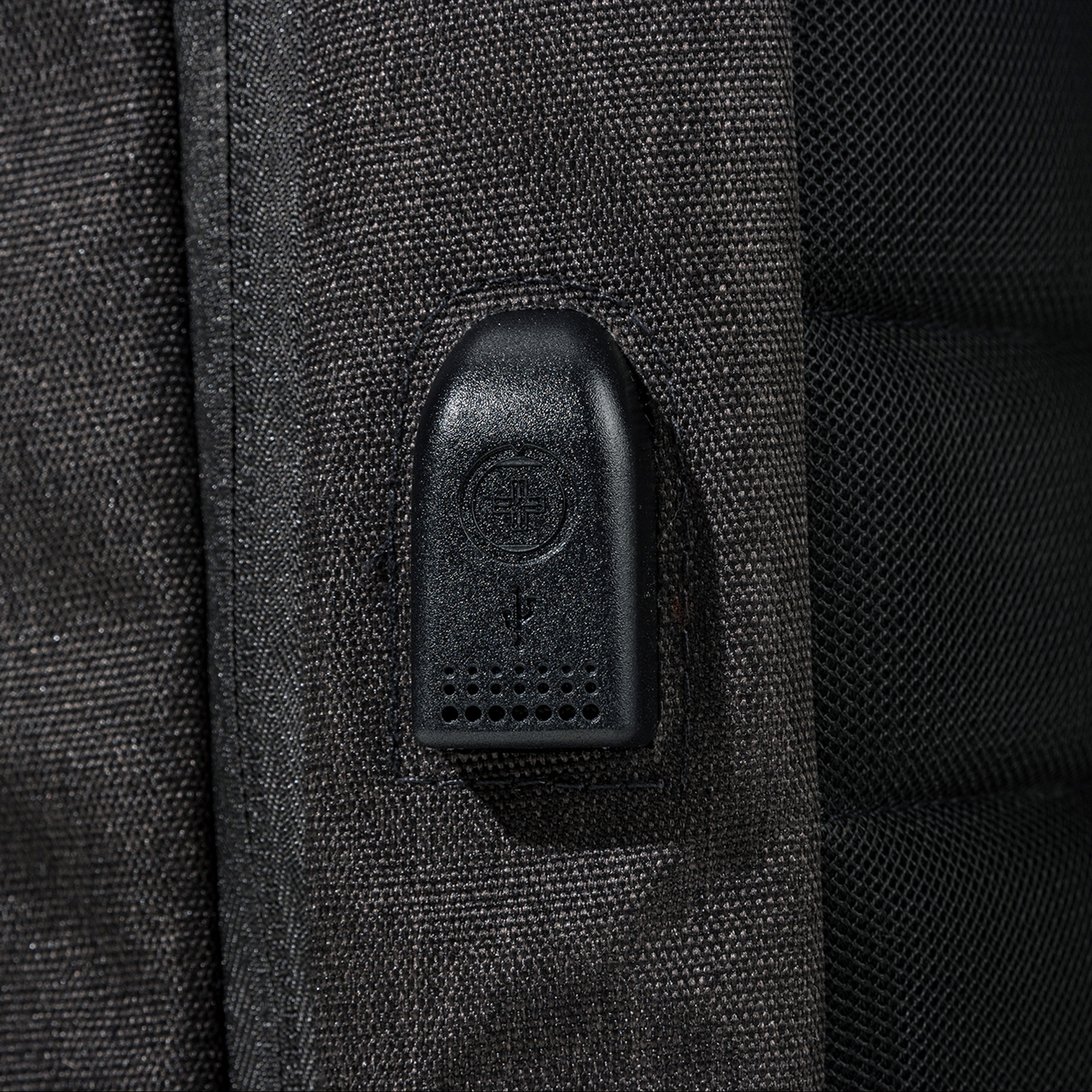 Primo piano di zaino nero con porta USB. Lo zaino è scuro e ha una superficie strutturata.