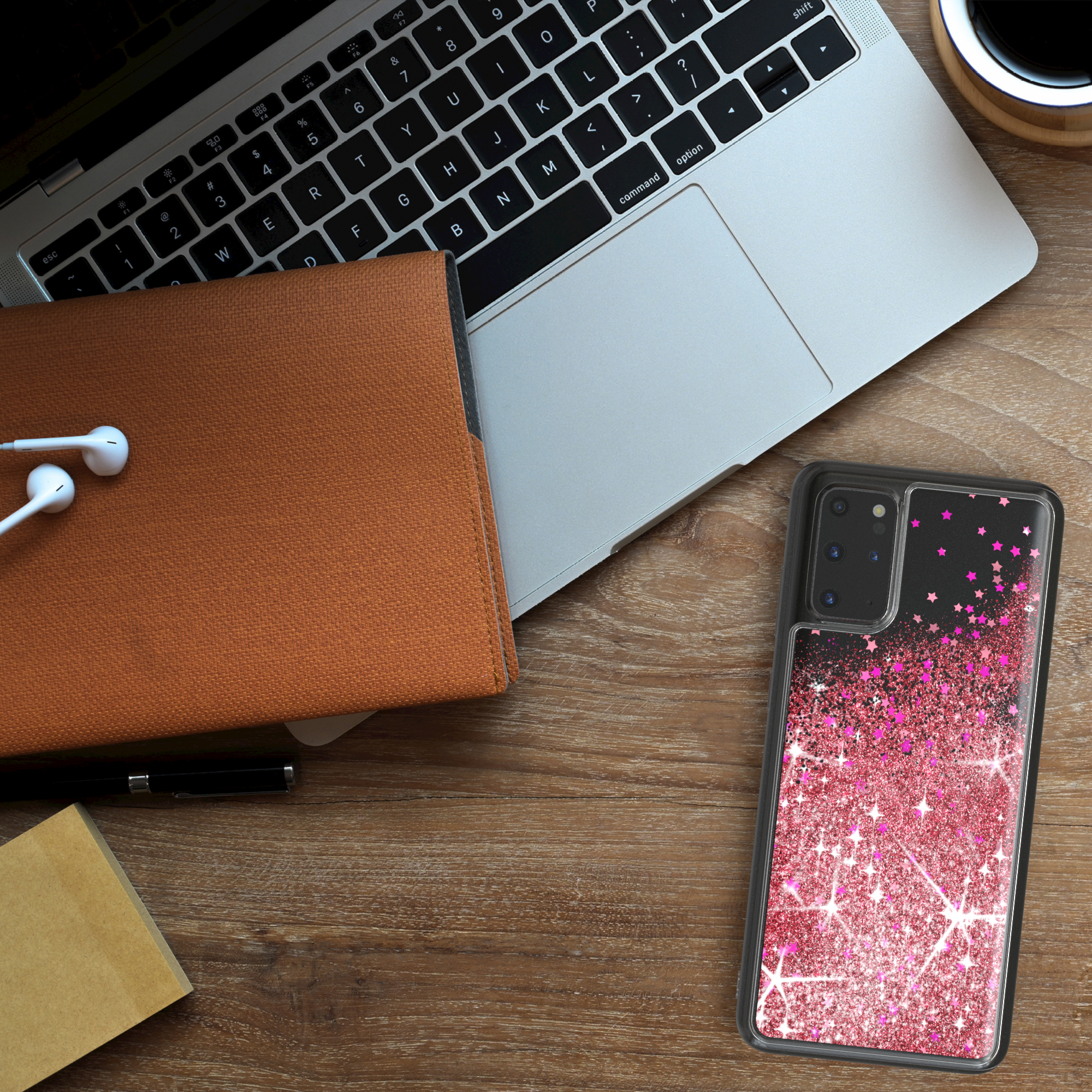 Handyhülle mit rosa Glitzer und Sternen auf einem Holzschreibtisch.