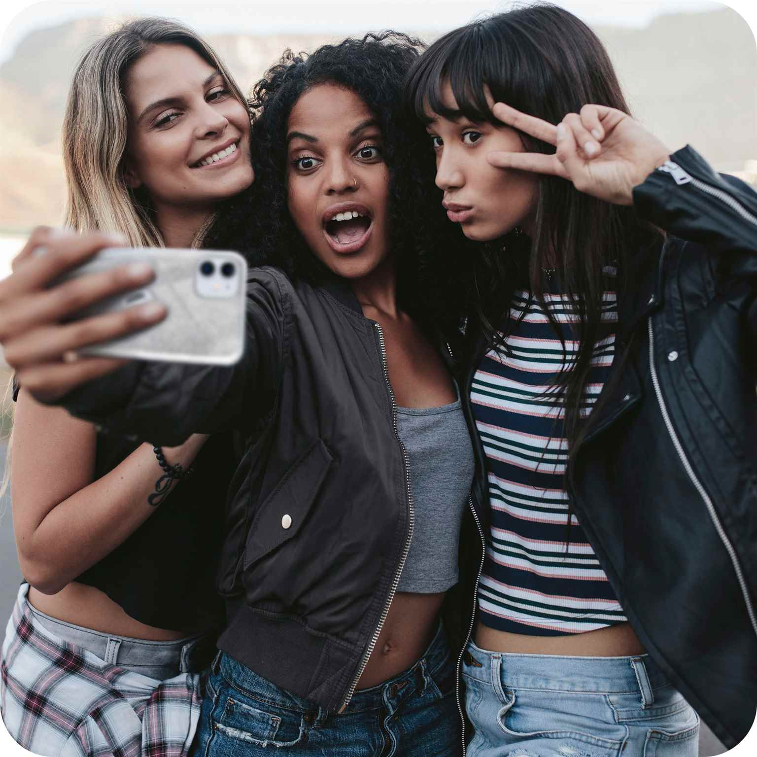 Drei Frauen machen ein Selfie. Eine hält das Telefon.