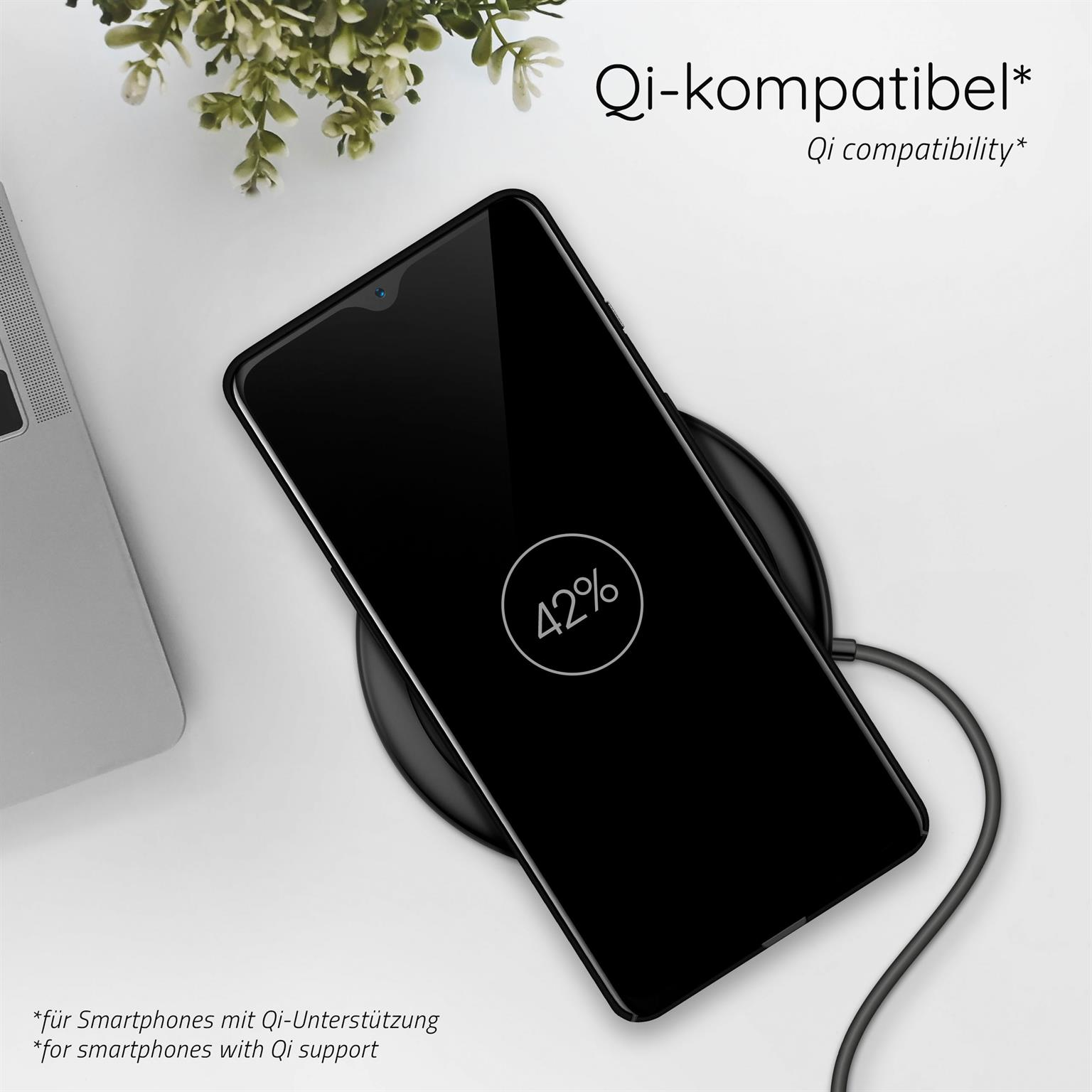 Ein schwarzes Smartphone liegt auf einem kabellosen Ladegerät; Bildschirm zeigt 42%. Pflanze im Hintergrund.