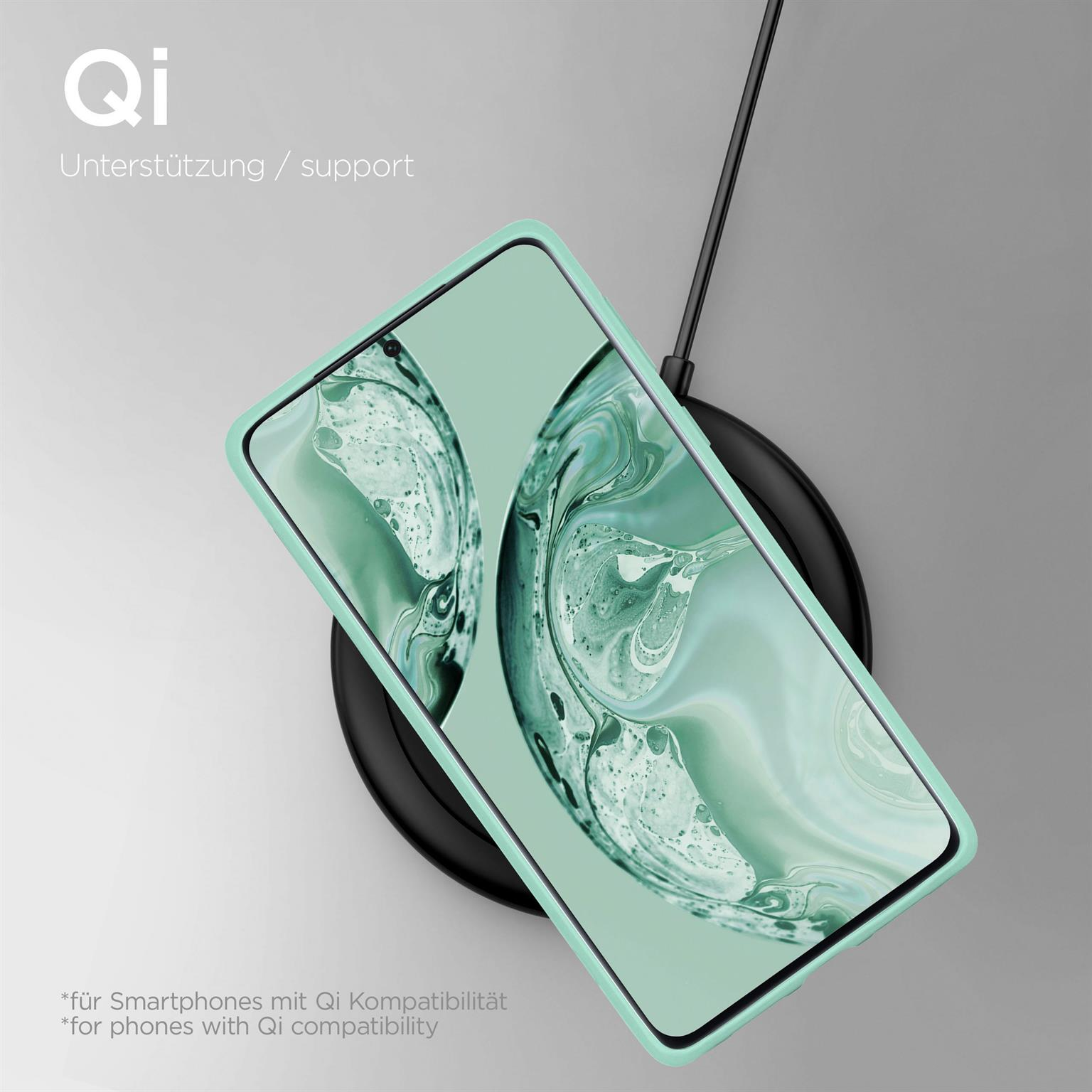 Telefon auf kabellosem Ladegerät. Text: Qi-Unterstützung. Das Telefon hat eine grüne Hülle.