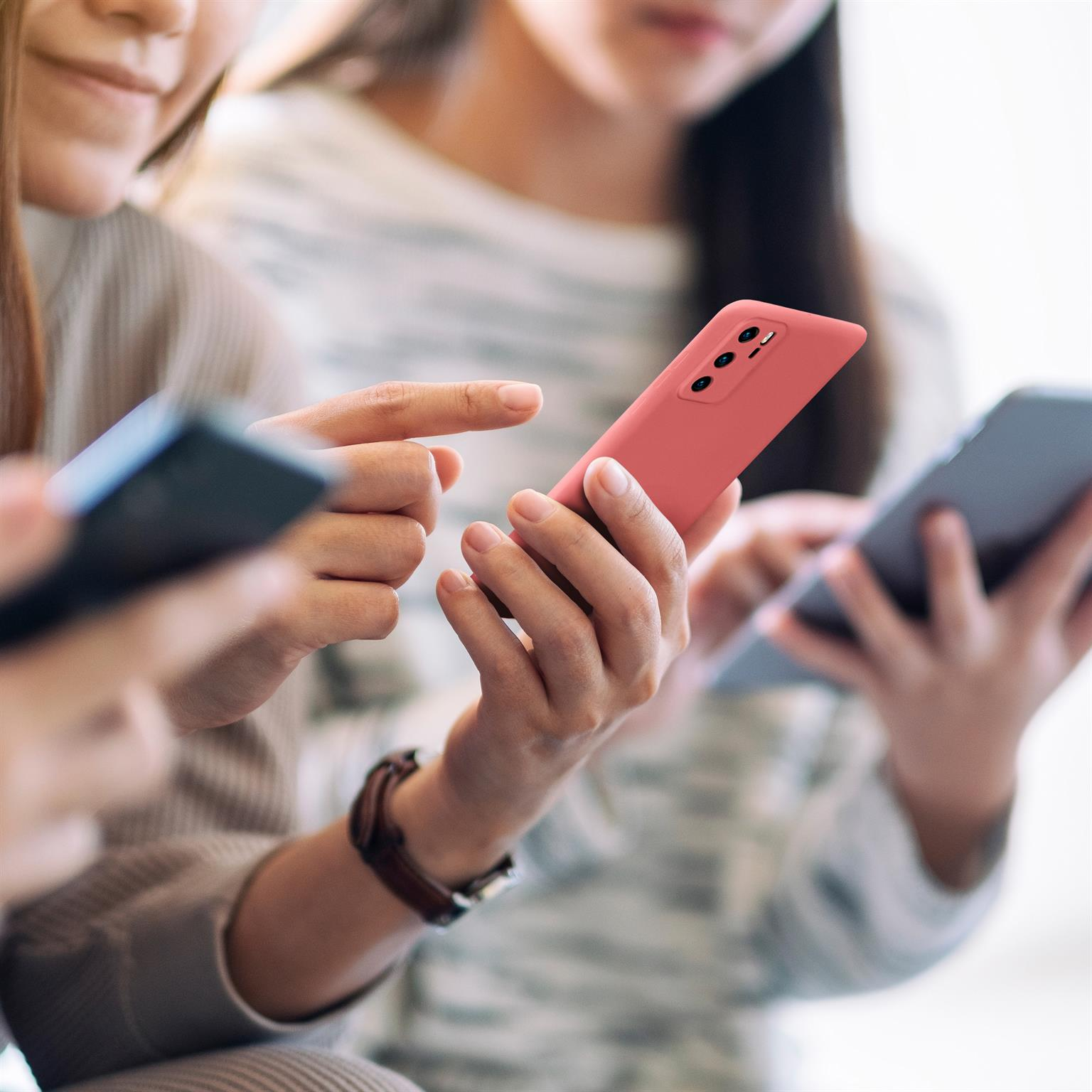 Drei Personen halten und benutzen Smartphones in verschiedenen Farben.