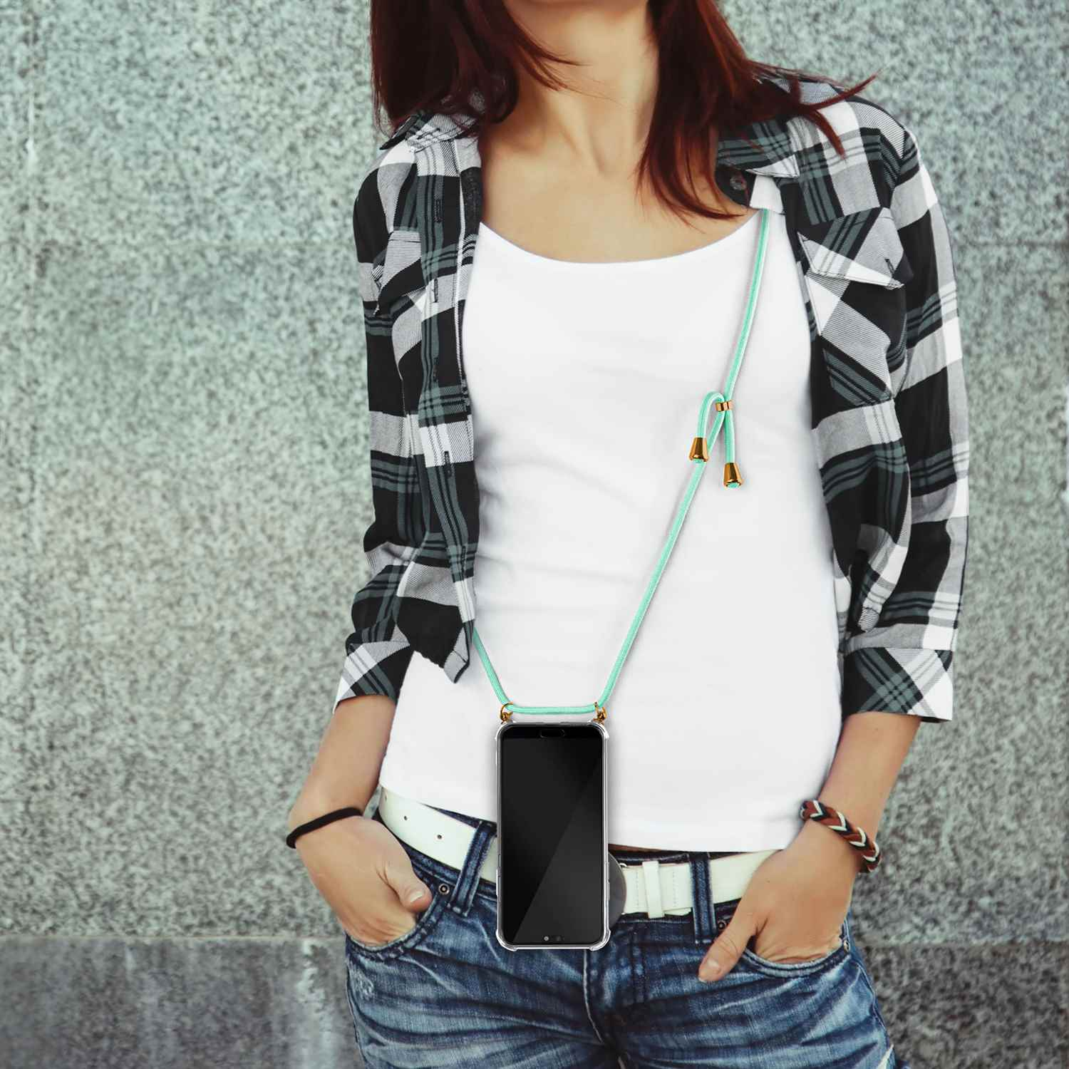Eine Frau im karierten Hemd mit Telefon an einem Lanyard um den Hals.