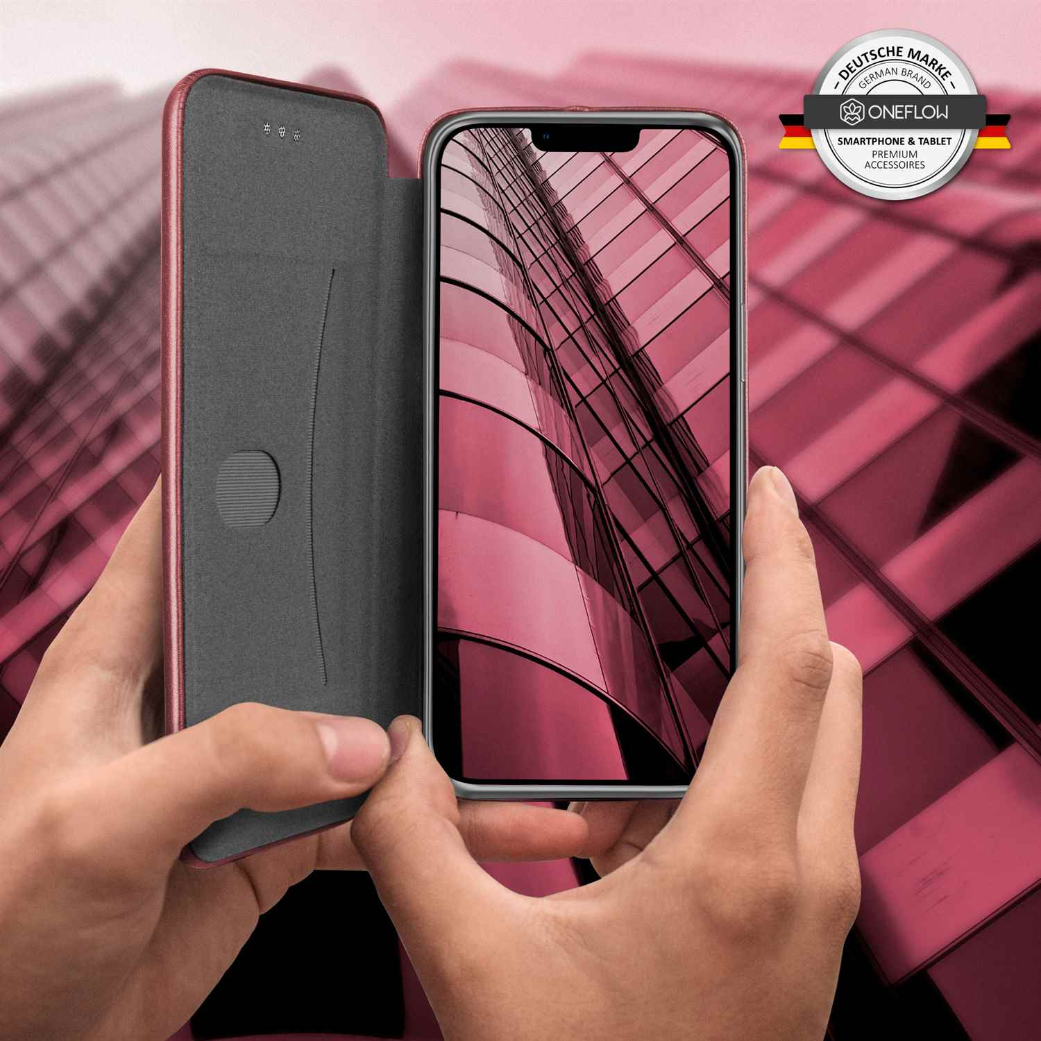 Hände einer Person, die eine Handyhülle halten, mit sichtbarem Telefonbildschirm, vor rosa Hintergrund.