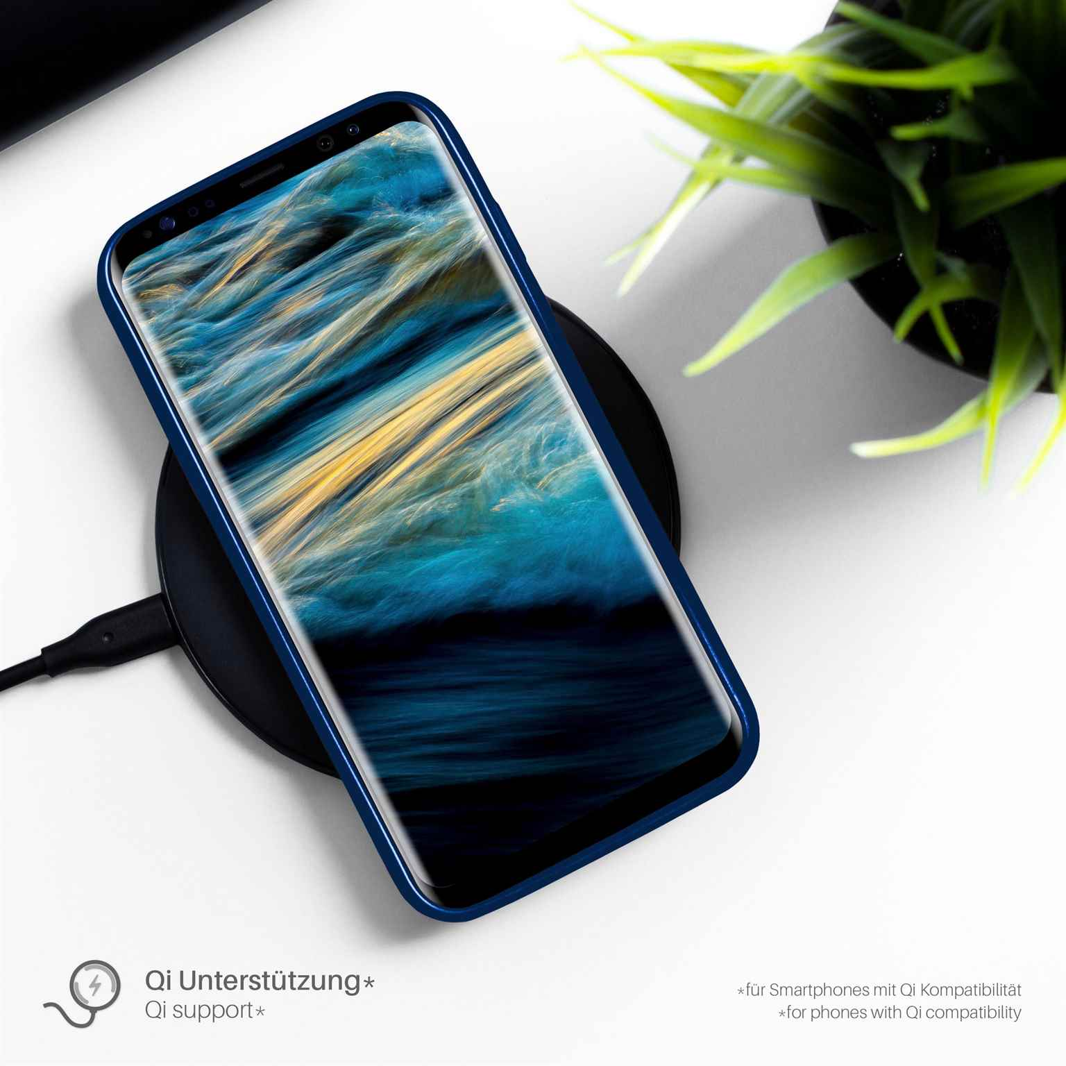 Telefon in blauer Hülle lädt auf schwarzem kabellosen Ladegerät mit grüner Pflanze im Hintergrund. Text 'Qi support'.
