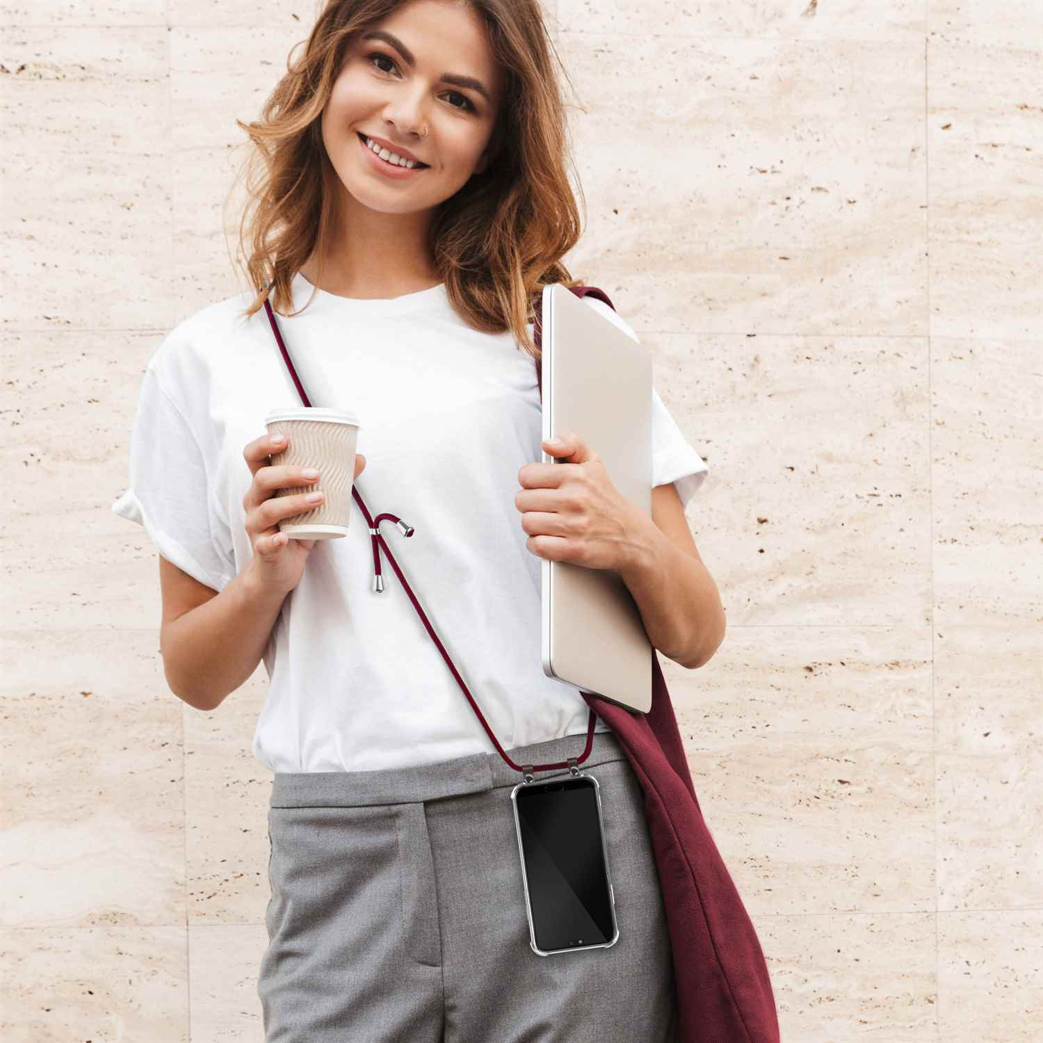 Eine Frau hält eine Kaffeetasse und einen Laptop. Ihr Handy ist an einem roten Lanyard.
