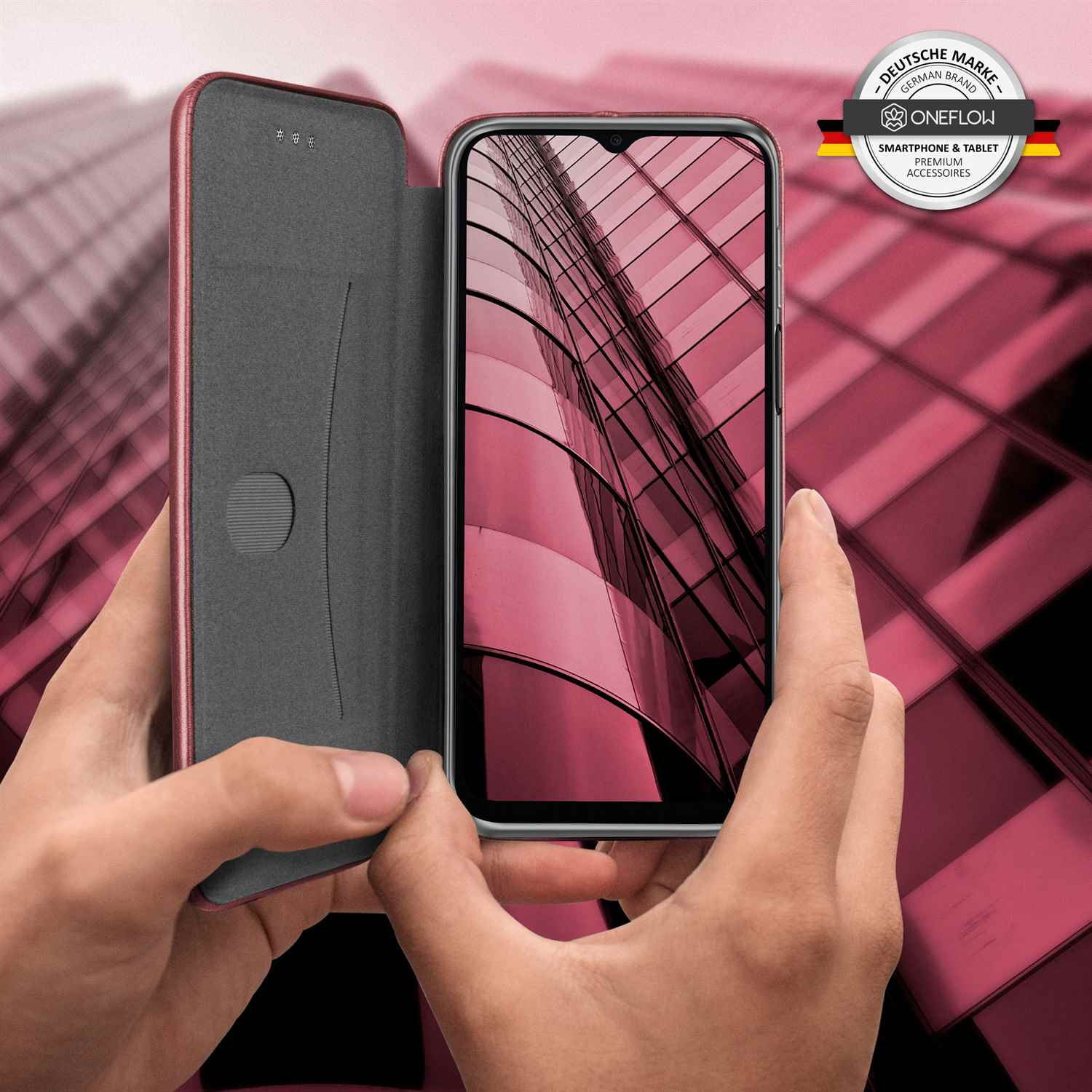 Hände halten eine Handyhülle mit einem Telefon darin, mit einem rosa Hintergrund.