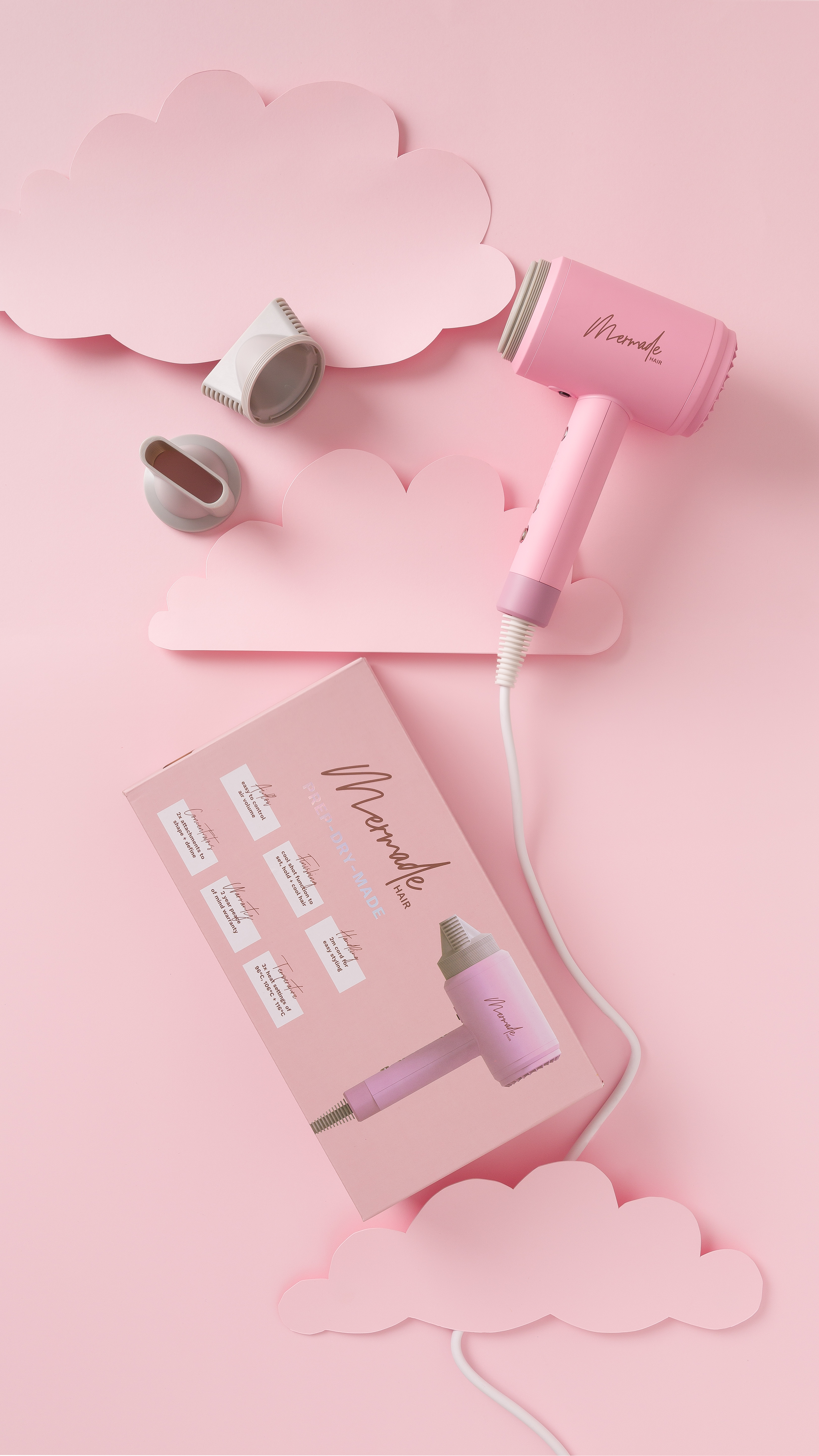 Pinker Haartrockner mit Zubehör und einer Box auf pinkfarbenem Hintergrund.