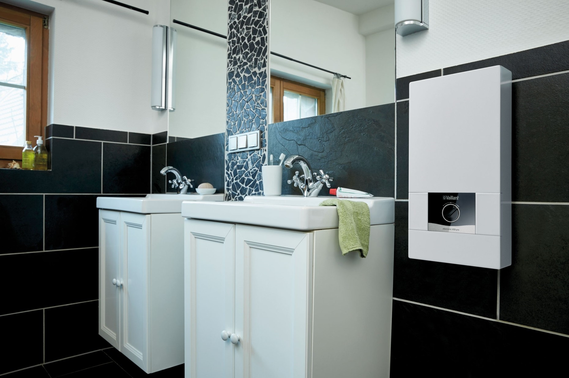 Modernes Badezimmer mit zwei Waschbecken, schwarzen Fliesen und einem weißen Heizkessel.