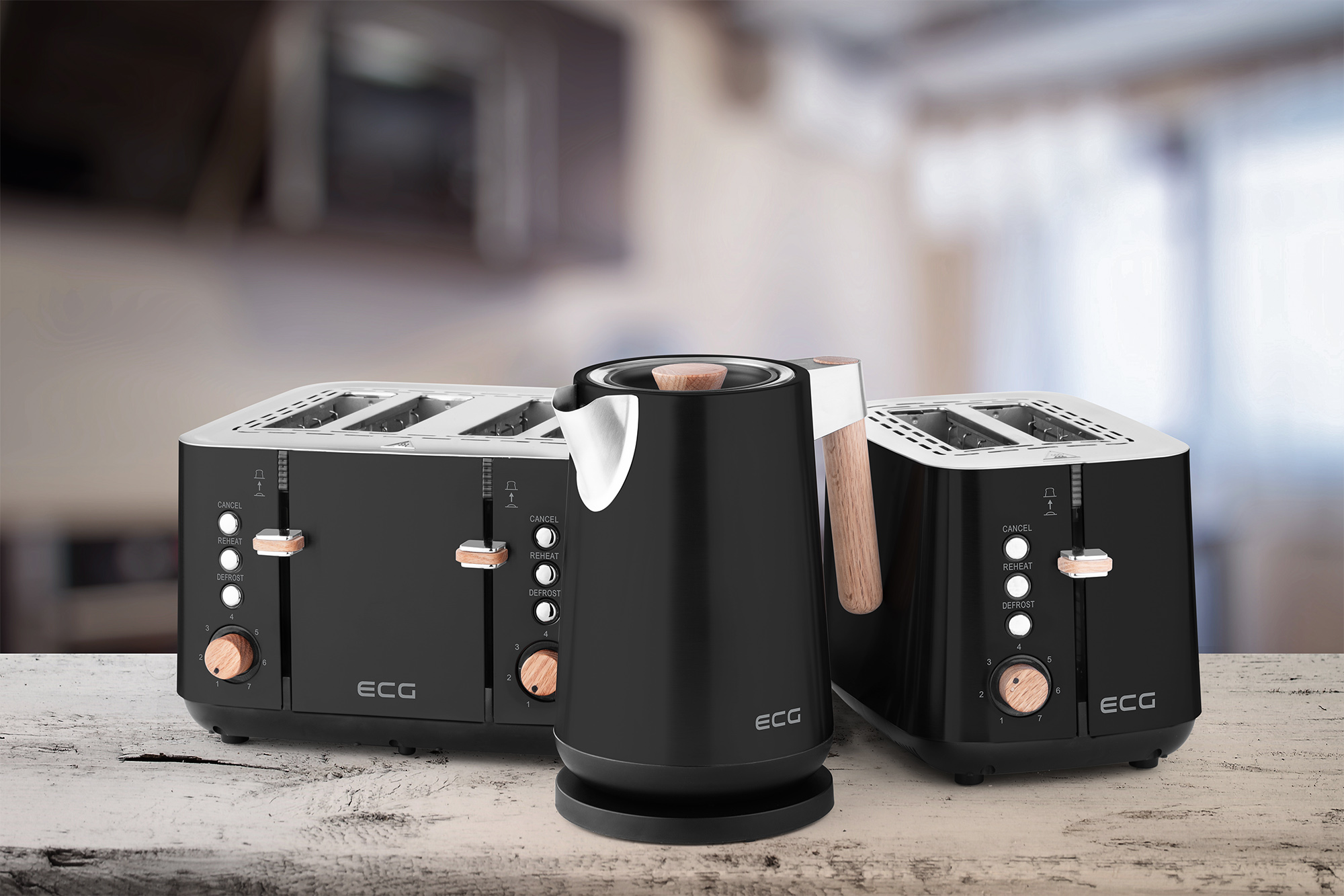 Czarny toster, czajnik i dwa tostery, z drewnianymi akcentami na drewnianym stole. Rozmyte tło.
