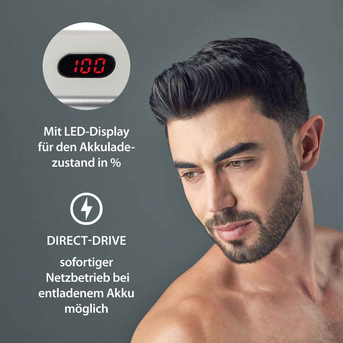 Mężczyzna z brodą patrzy w dół. Mały wyświetlacz pokazuje 100% baterii. Szare tło.