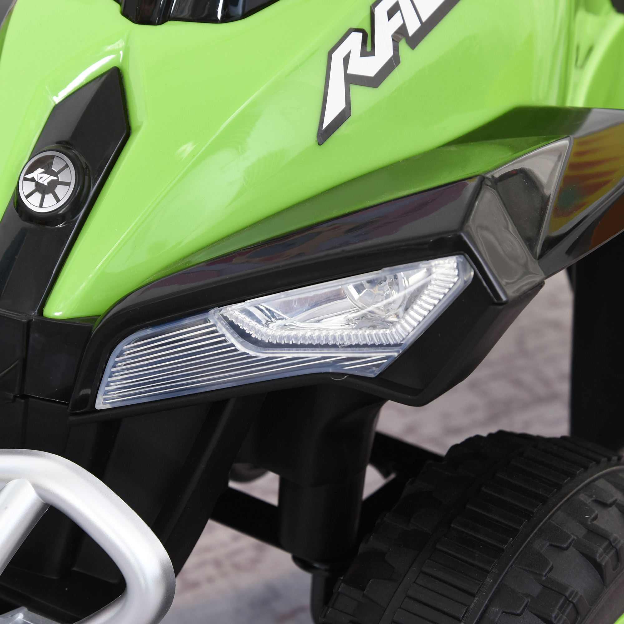 Juguete ATV verde y negro con faro brillante y barra plateada.