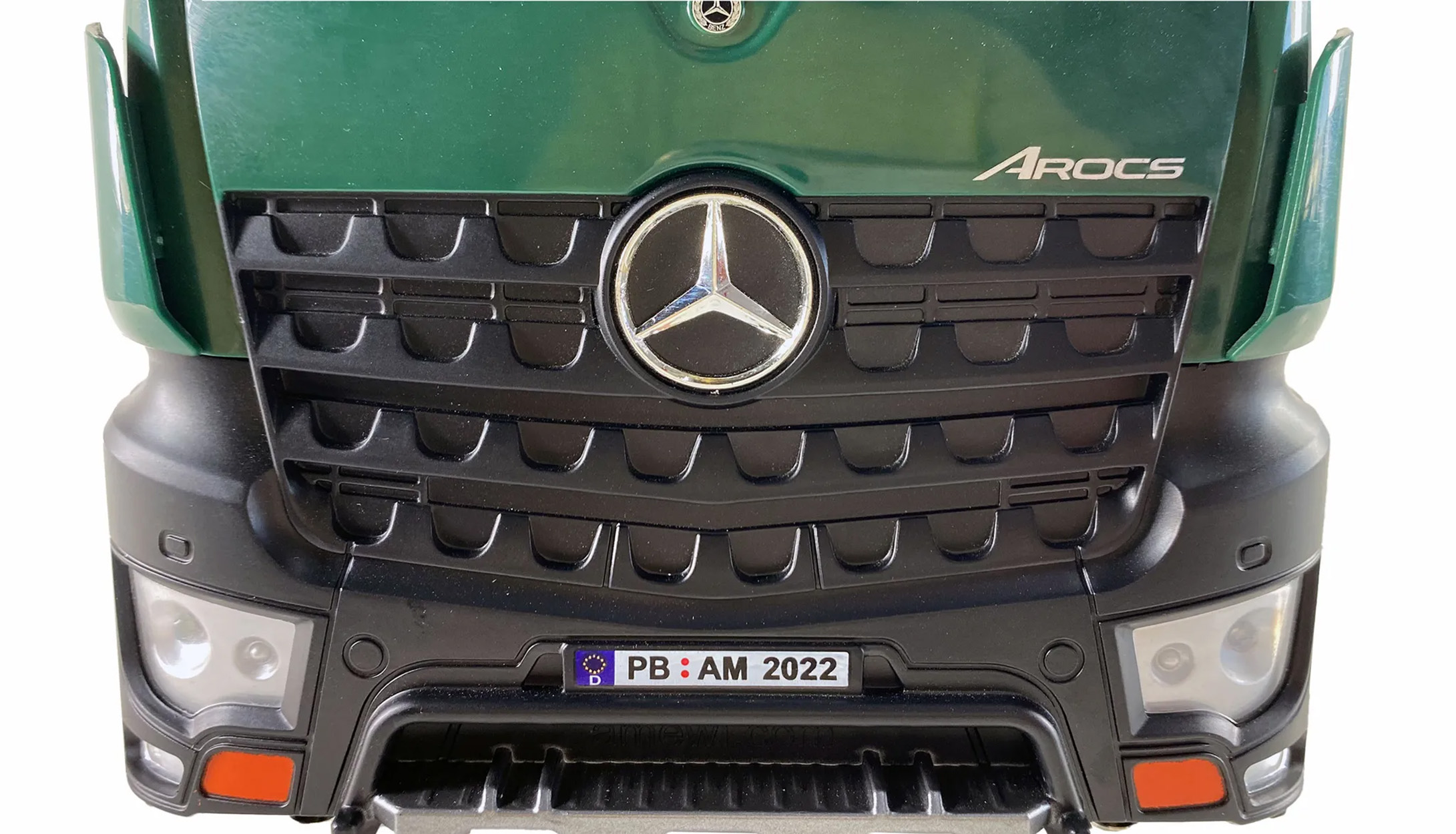 Nahaufnahme der Front eines grünen Mercedes-Trucks. Schwarzer Kühlergrill, Logo und Nummernschild.