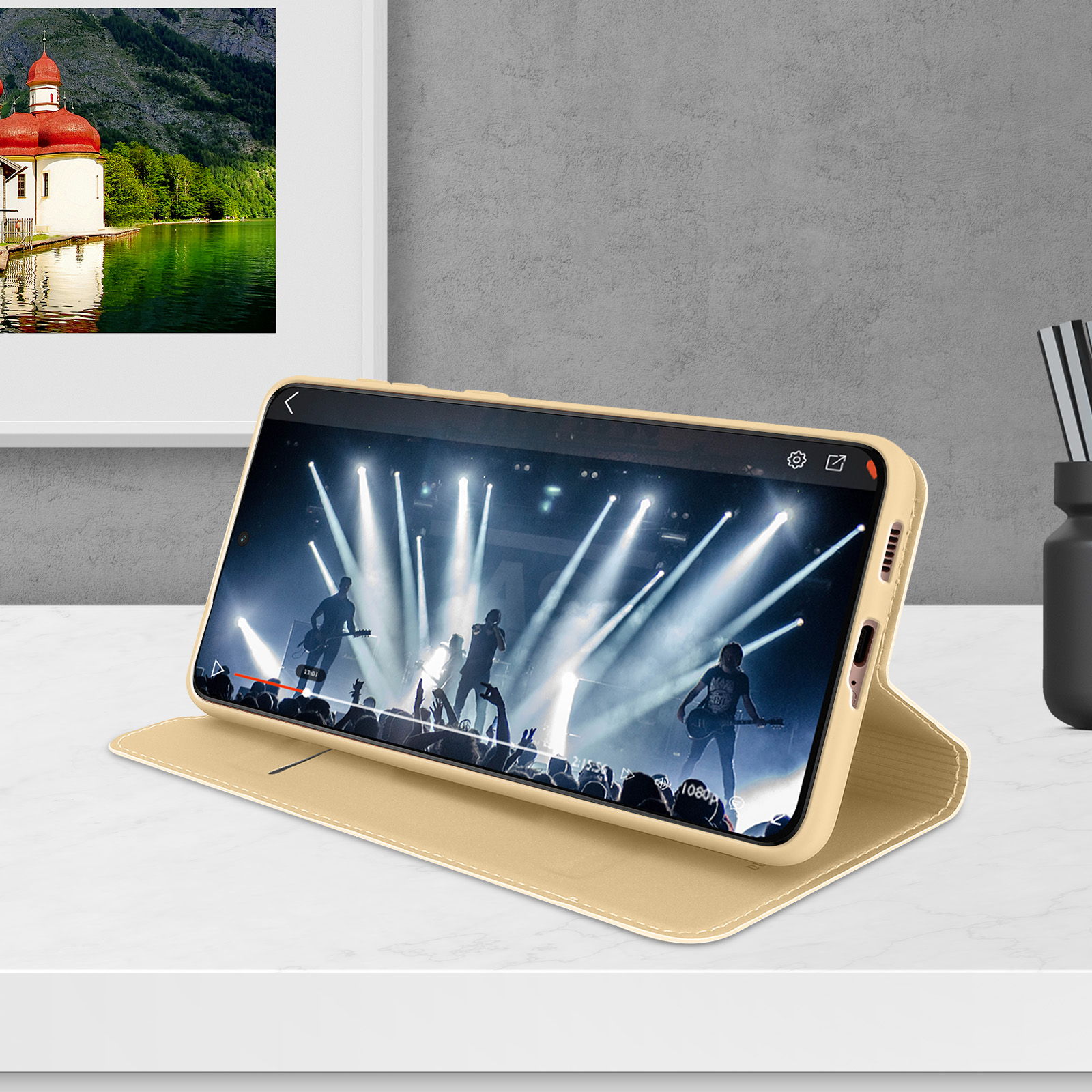 Ein Handy mit Konzertvideo, mit See und Bergen im Hintergrund.
