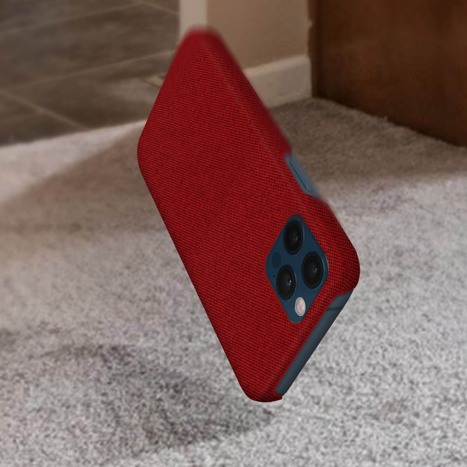 Custodia rossa che cade su moquette grigia. La custodia ha tre lenti.